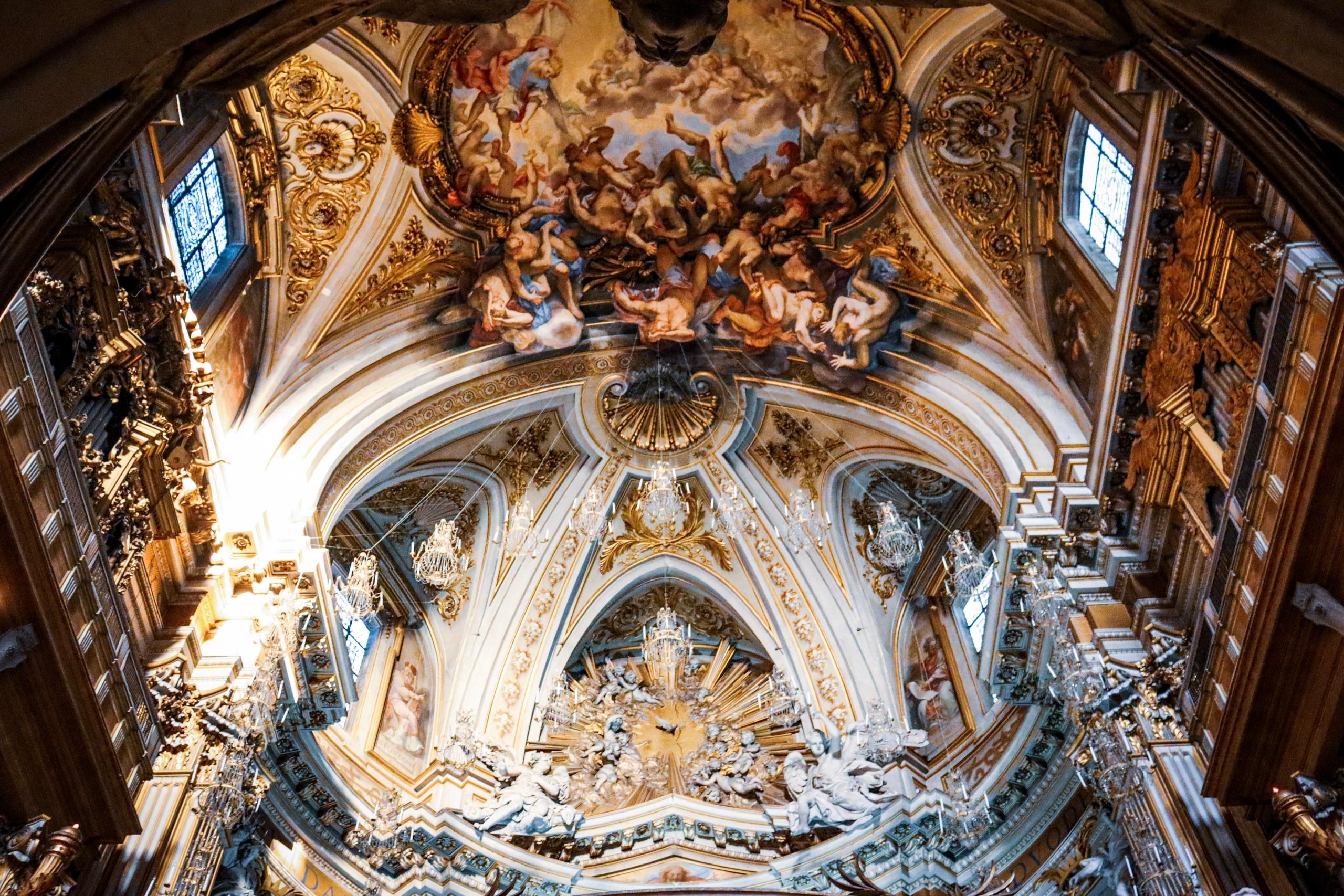 Eine Kirchendecke erstreckt sich, verziert mit Malereien und Fresken.
