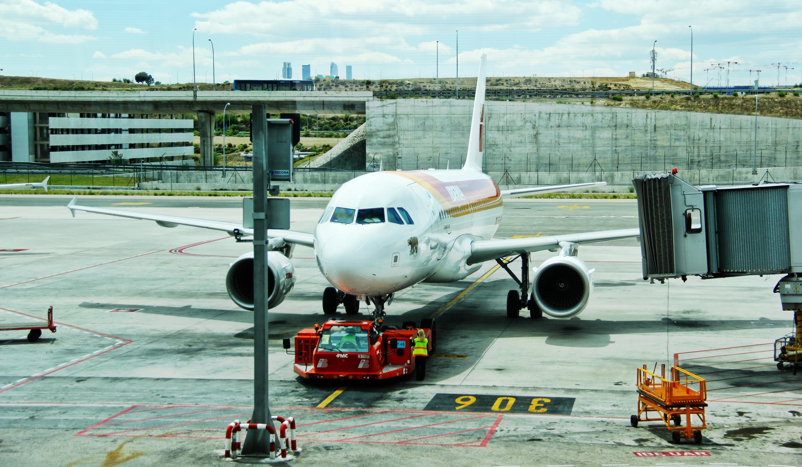 Ein Flugzeug steht auf dem Rollfeld und wird von einem roten Wagen gezogen.