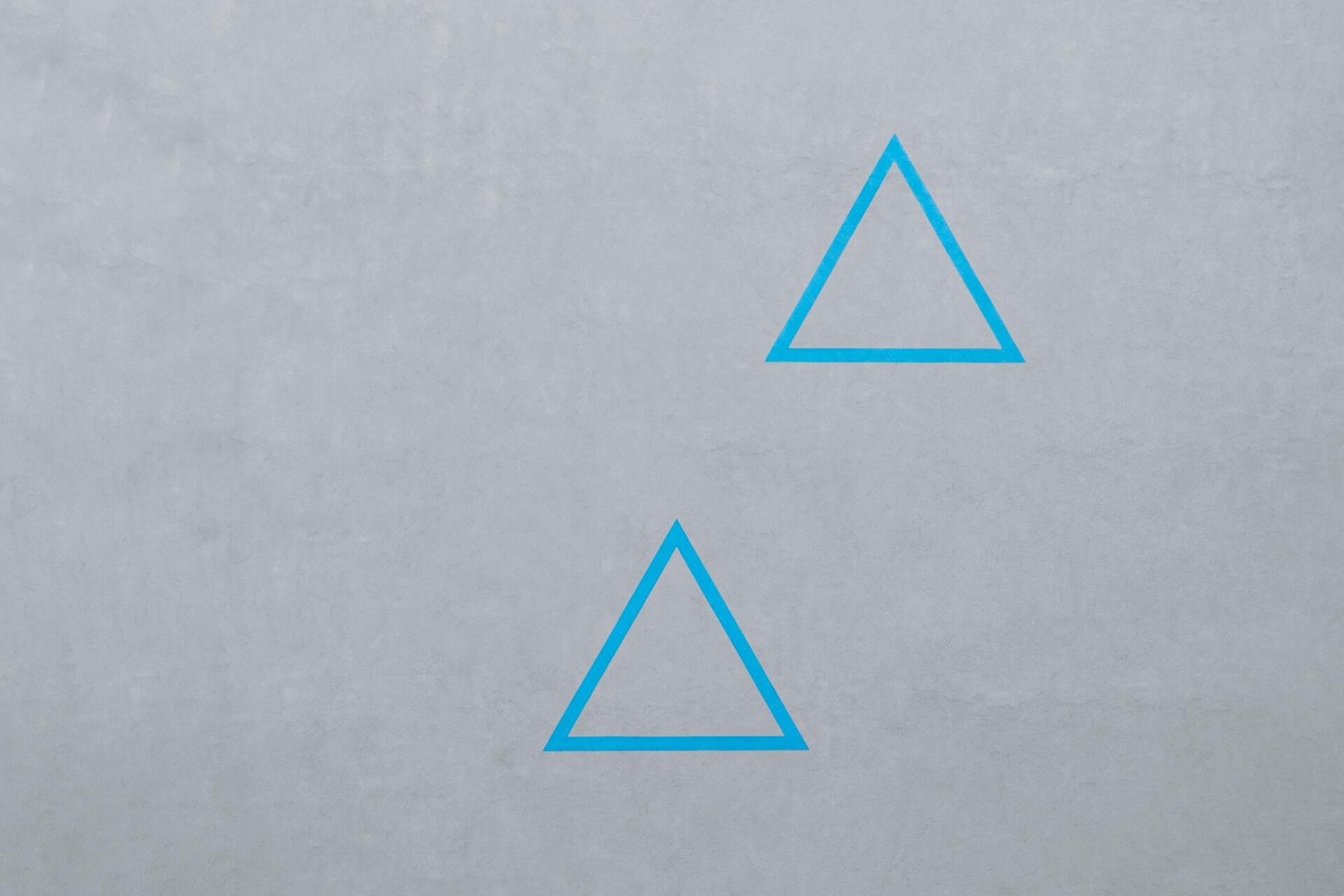 Zwei blaue Dreiecke auf grauem Hintergrund.