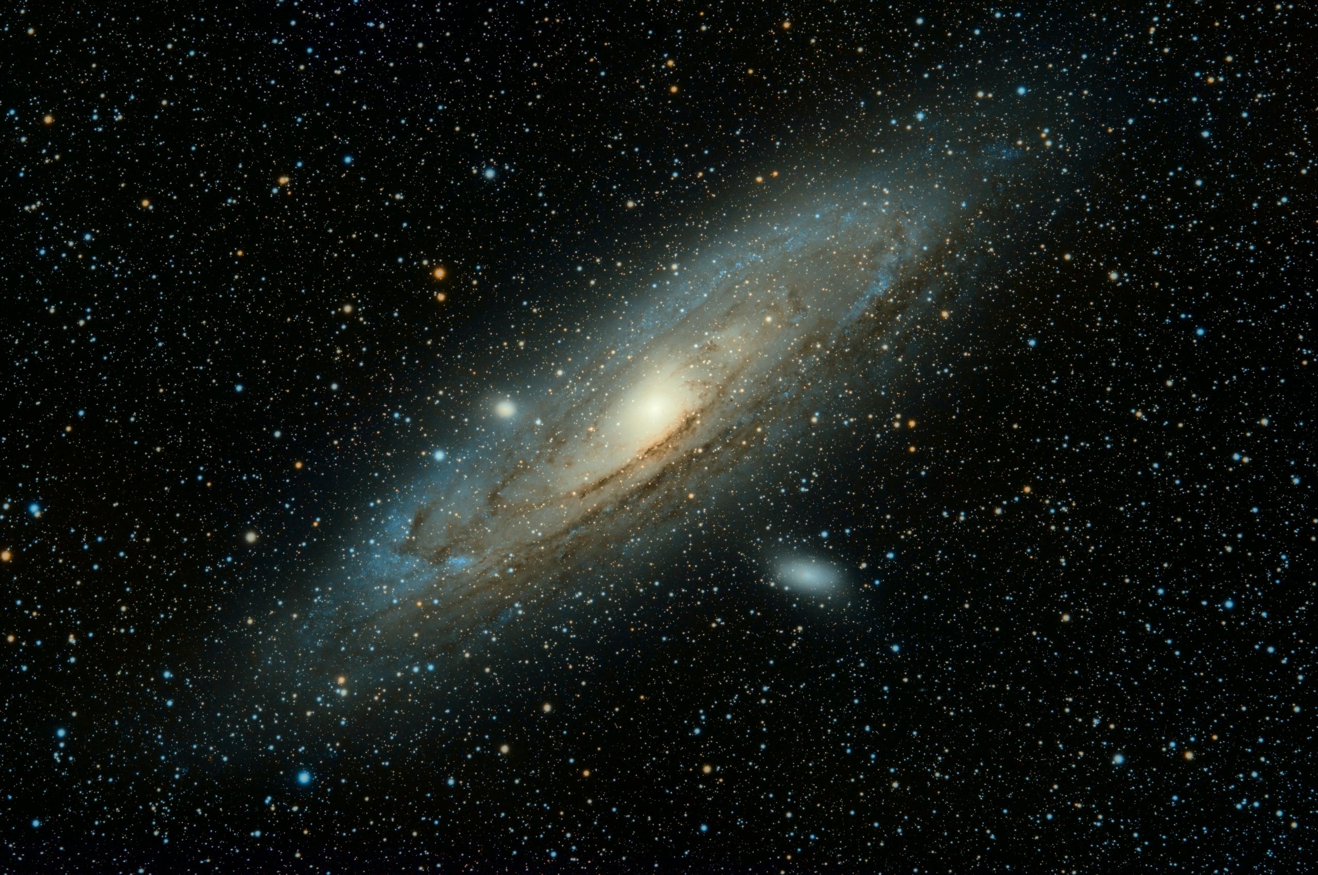 Vor einem schwarzen Himmel mit zahlreichen Sternen ist eine Galaxie in weiß und gelb.