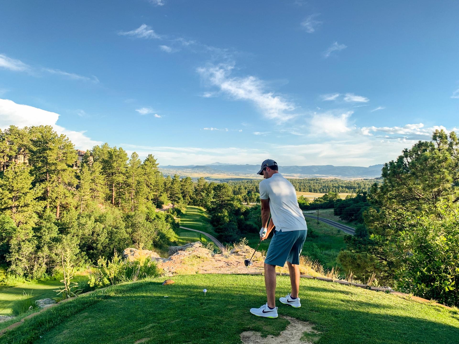 Eine Person steht auf dem Golfplatz im Grünen und mit Meerblick bei schönem Wetter