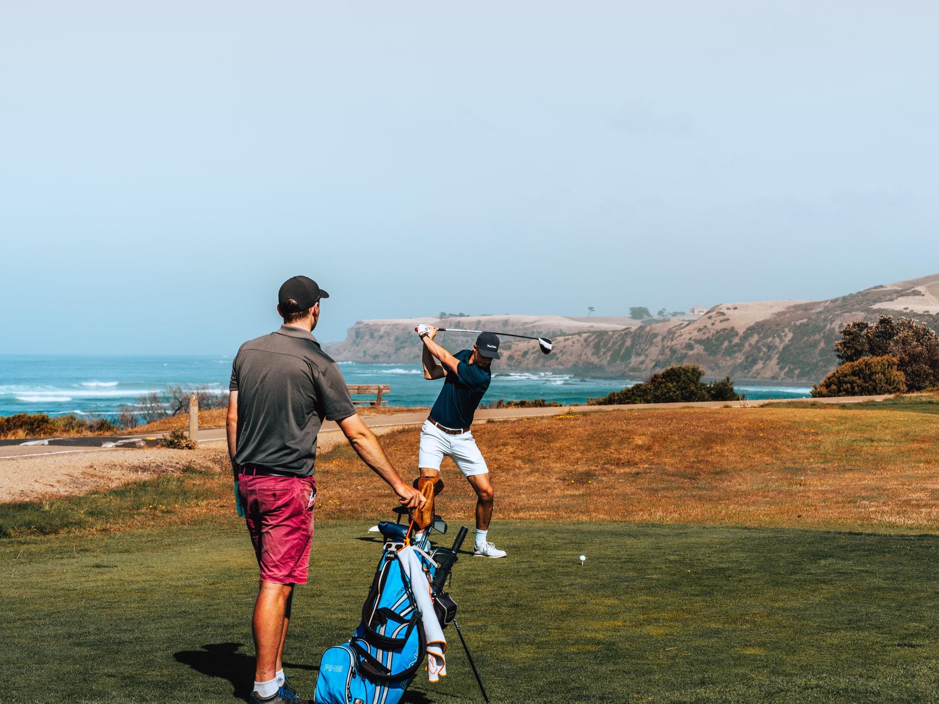 Zwei Personen spielen Golf auf einem Platz an der Küste mit Blicks aufs Meer