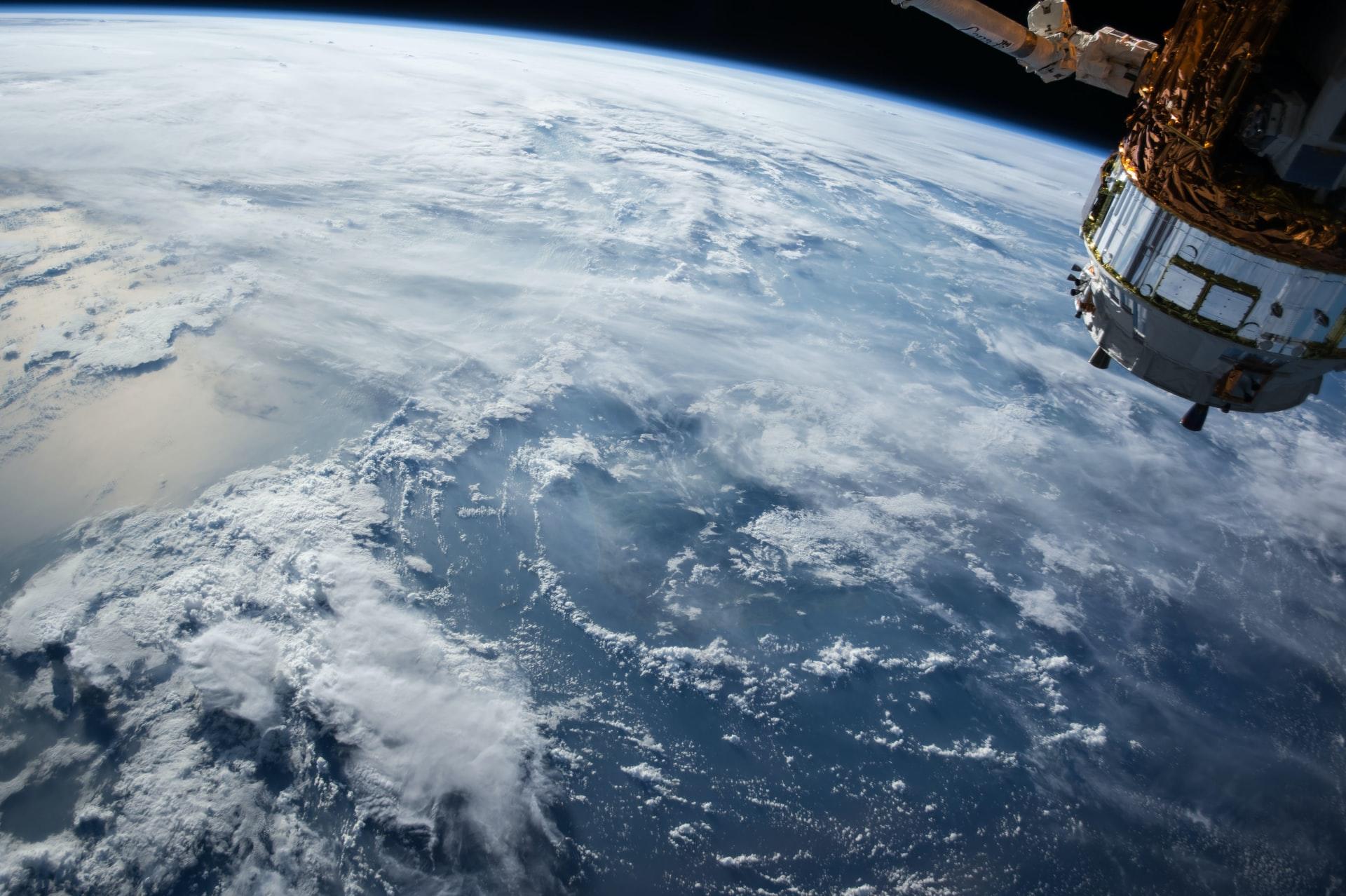 Ein Satellit im Weltall blickt auf die Erde mit Wolken von oben.