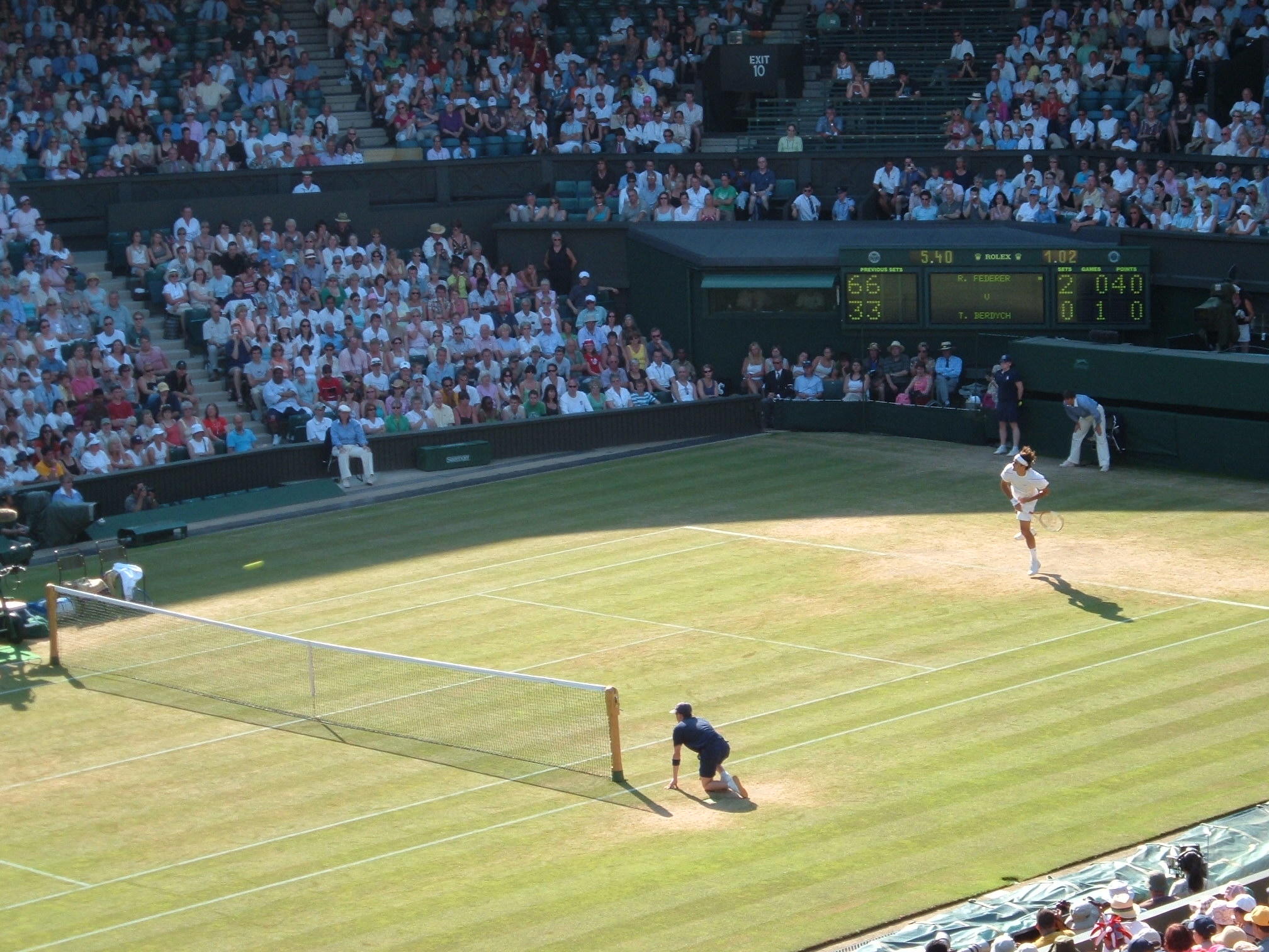 Ein Tennisspiel auf Rasen vor gefüllten Zuschauerrängen.