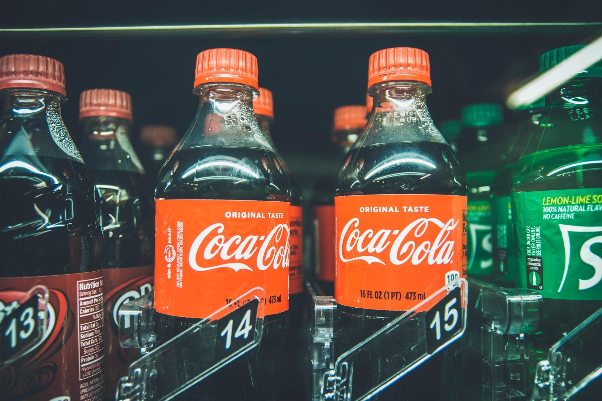 Colaflaschen stehen in einem Getränkeautomaten neben anderen Softdrinks