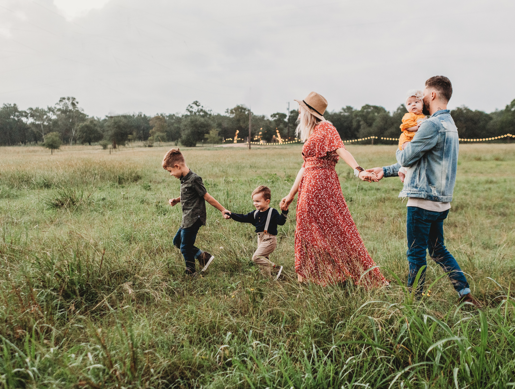 Eine Familie mit drei Kindern läuft über eine Wiese. Das älteste Kind geht vorneweg. Die Einschulung ist eine Veränderung für die Familie.