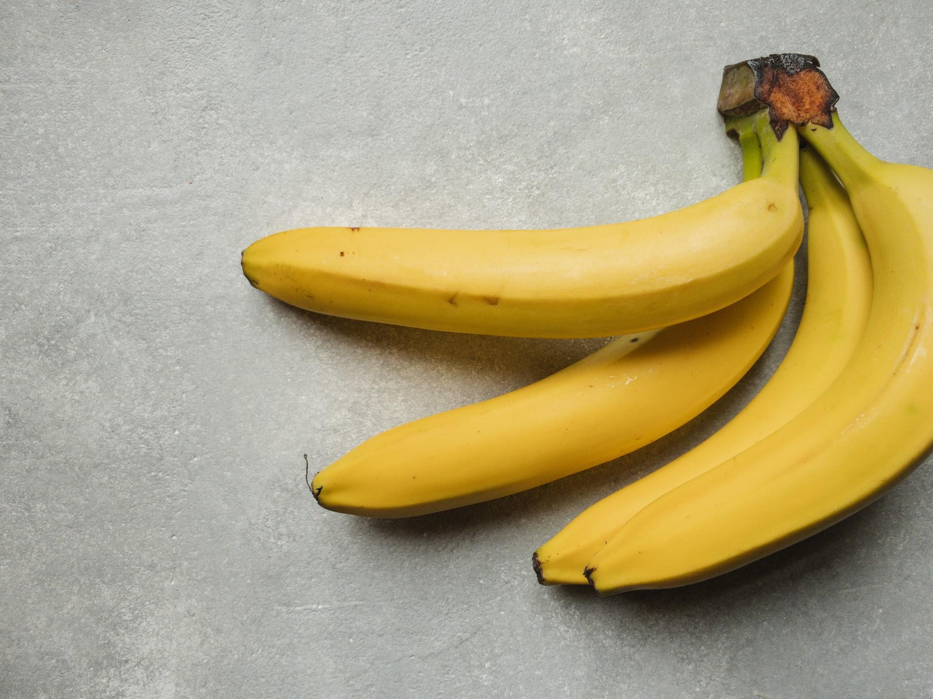 Bananen wie hier auf grauem Untergrund abgebildet essen Fahrer der Tour de France als Zwischenstärkung.