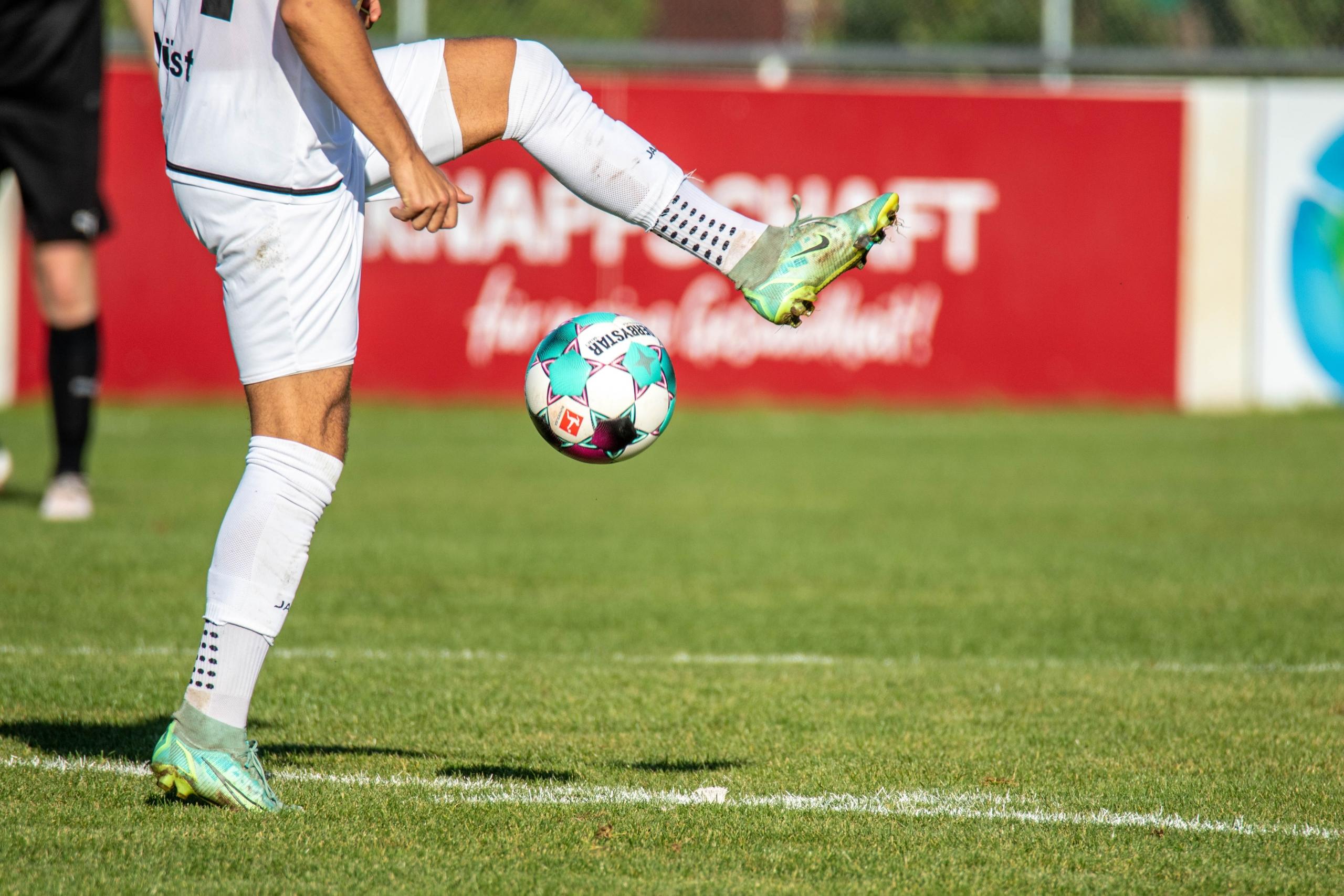 Ein Fußballspieler hält den Ball hoch und führt dabei Tricks aus. Durch die Professionalisierung des Fußballs ist das Niveau der Spieler rasant angestiegen.