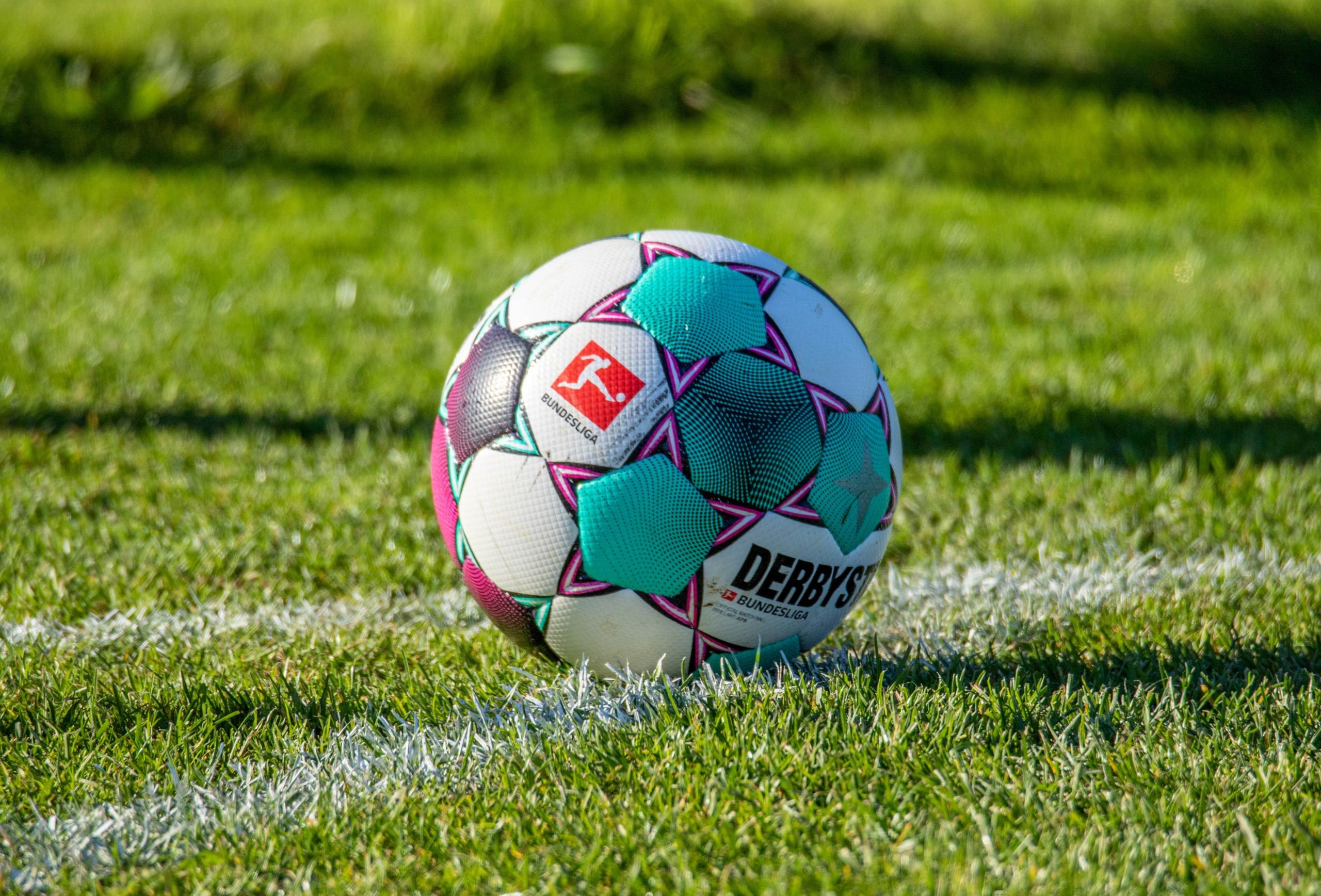 Ein Spielball der Fußball-Bundesliga auf dem grünen Rasen. Es dauerte sehr lange, bis man unter einem gemeinsamen Logo und einer gemeinsamen Idee in Deutschland Fußball spielte.