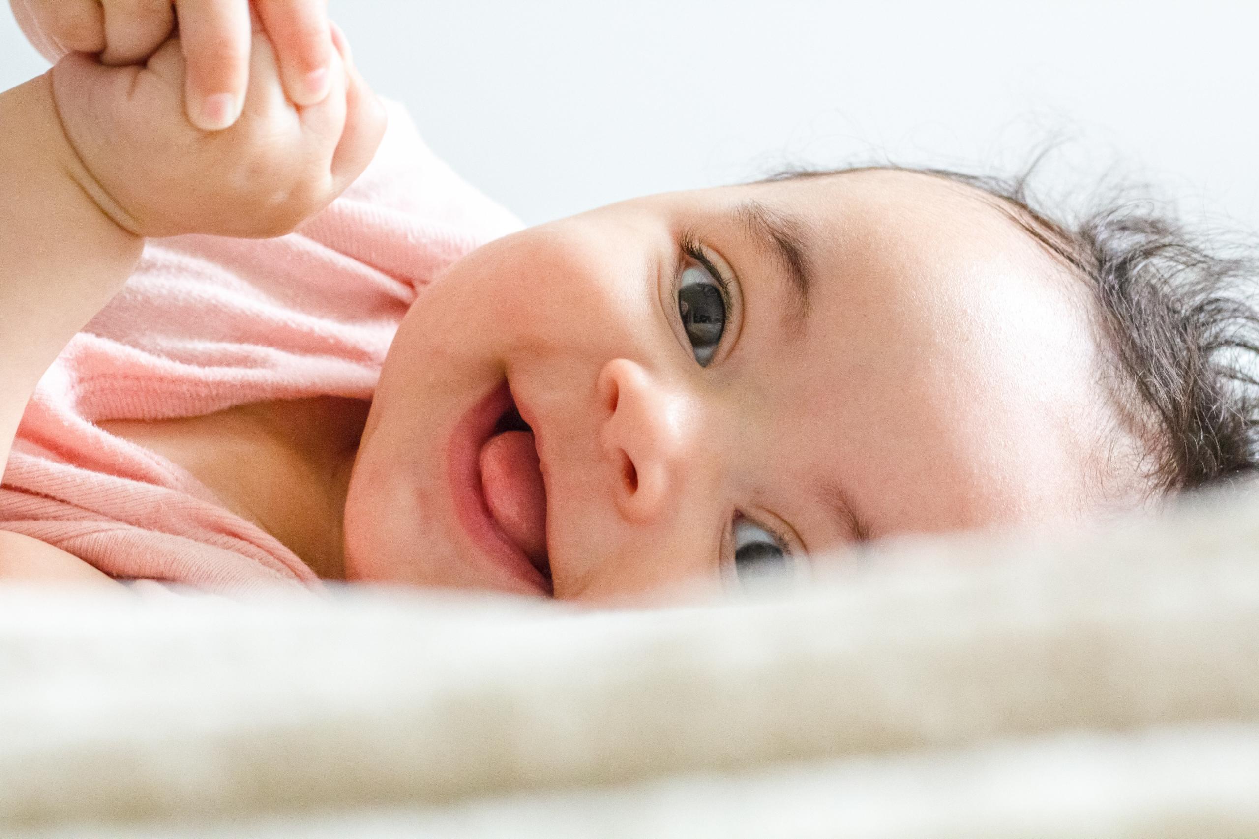 Ein Baby liegt strahlend auf einer Matte.