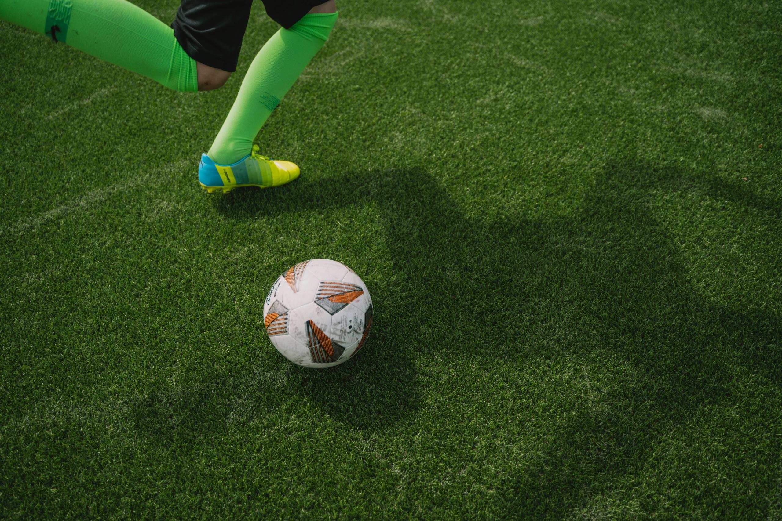 Ein Fußballspieler setzt zum Schuss an. Wenn sein Gegner den Ball trifft, bevor er den Stürmer berührt, liegt kein Foul vor.