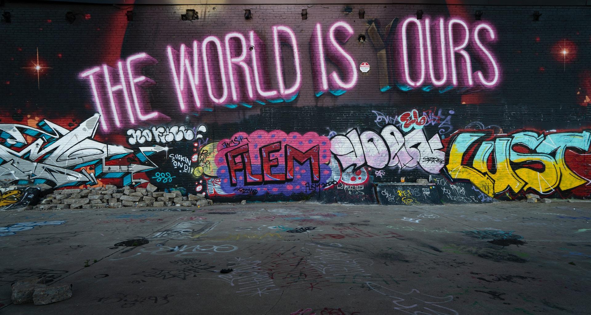 Auf einer mit Graffiti besprühten Wand steht in Leuchtschrift 