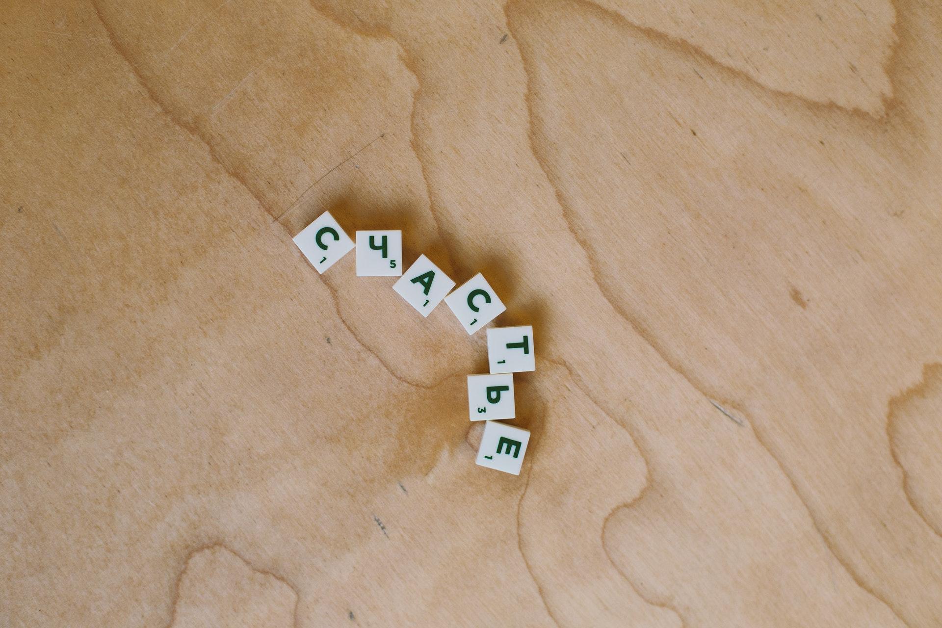 Auf einer Holzoberfläche liegen Scrabble-Steine und schreiben das russische Wort für Glück.