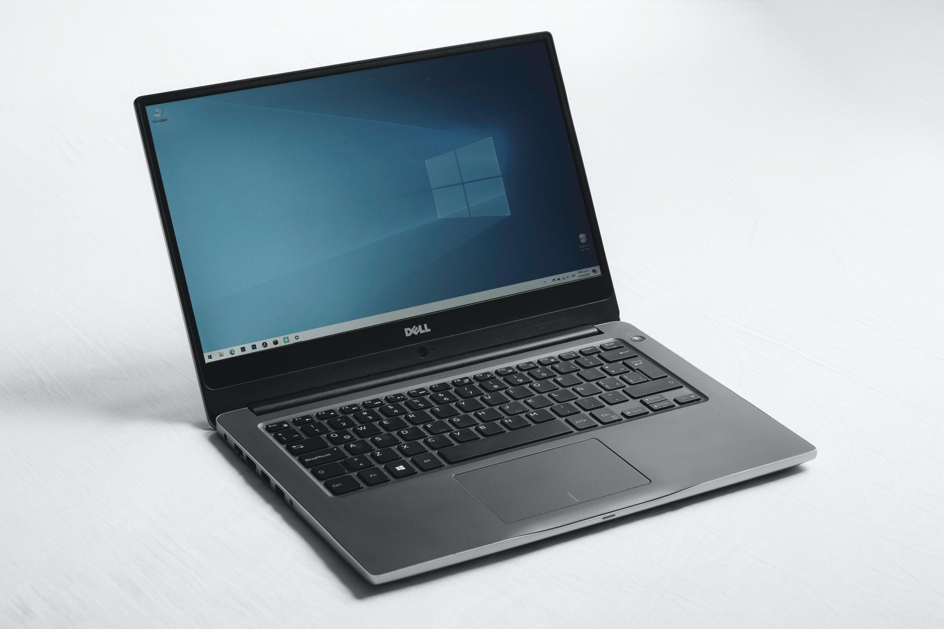 Ein geöffneter Laptop mit Windows-Startbildschirm steht vor weißem Hintergrund.