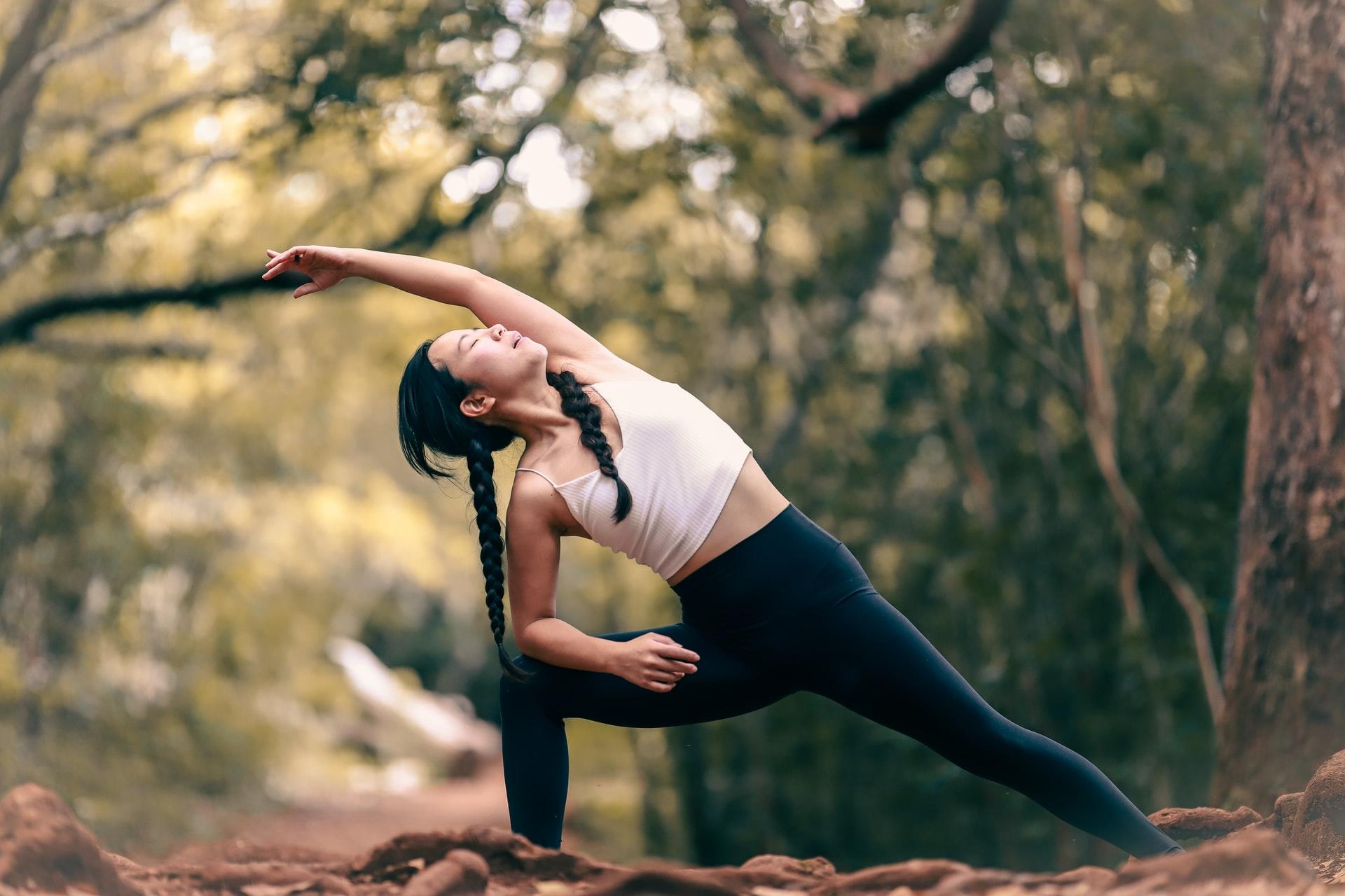 Eine Frau macht eine Yoga-Übung im Wald.