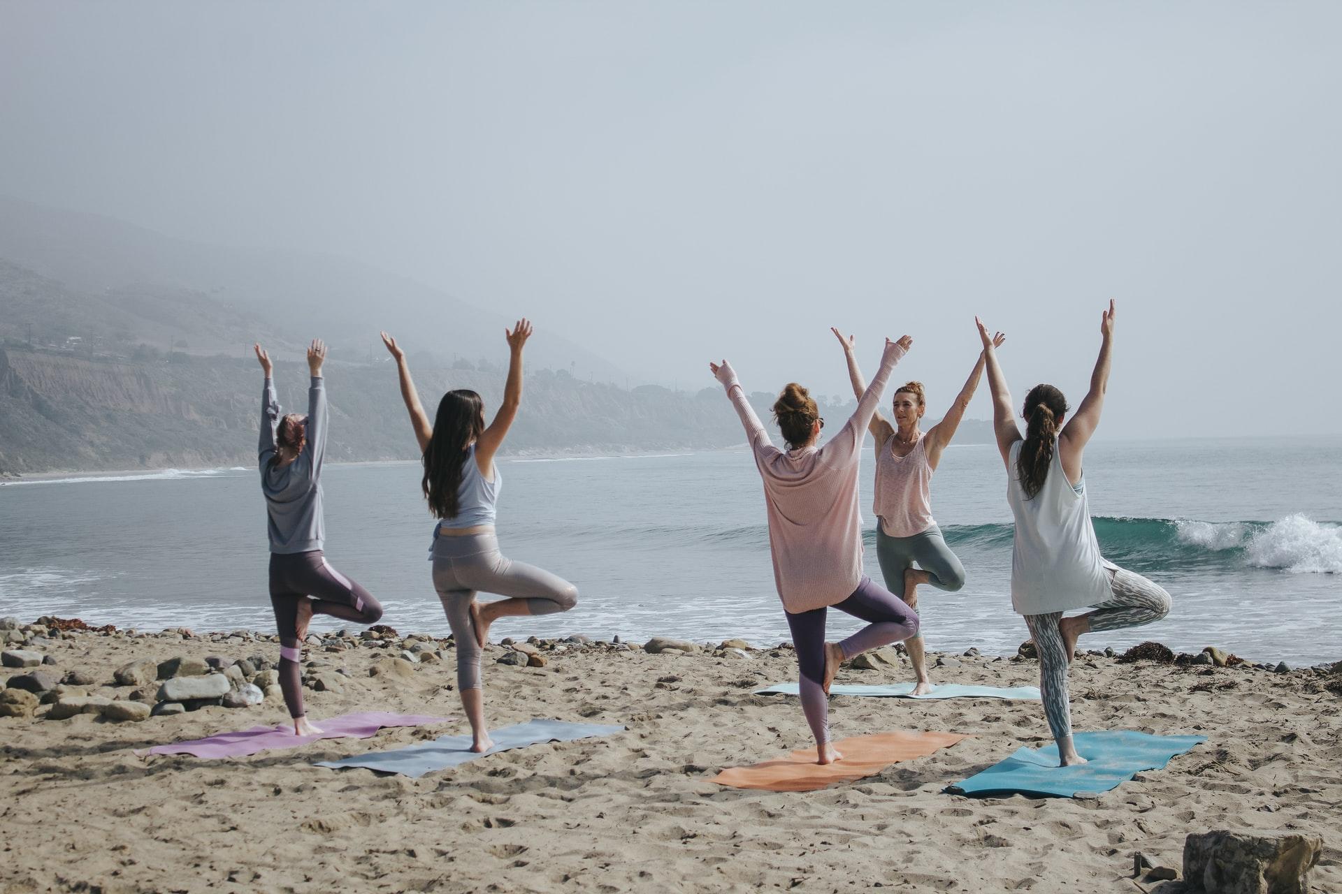 Eine Gruppe Menschen macht am Strand Yoga.