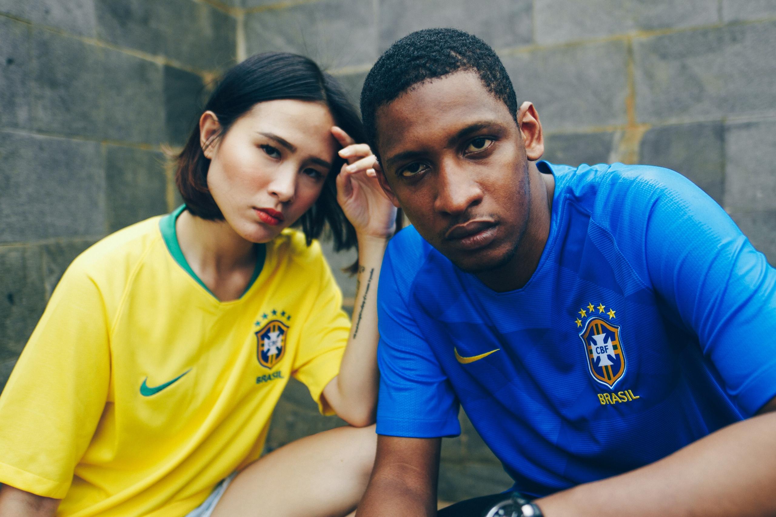 Eine Frau und ein Mann in brasilianischen Fussball-Trikots blicken mit ernsten Gesichtern in die Kamera. 