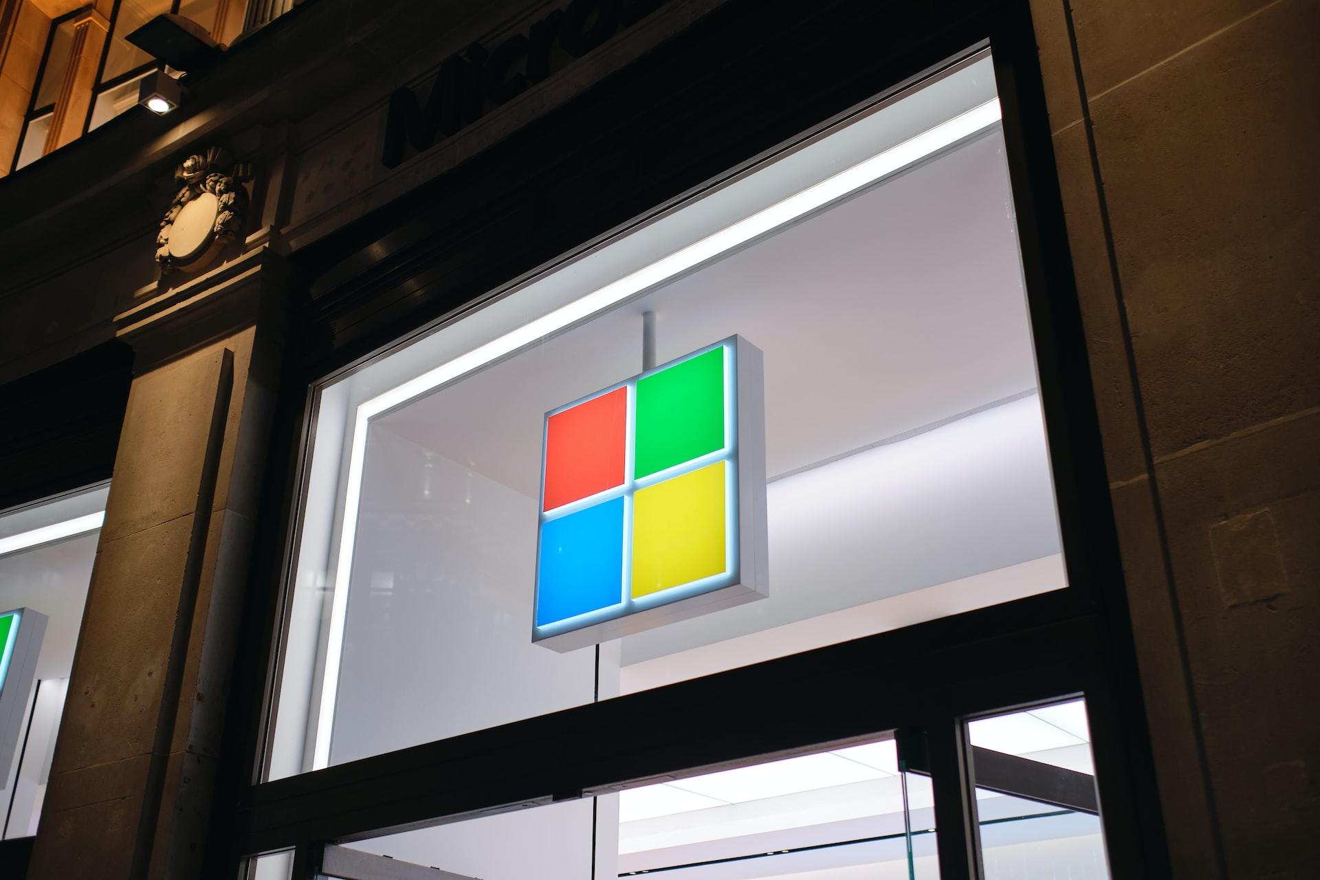 Auf einem beleuchteten Fenster ist das Microsoft-Logo über einer Tür angebracht.