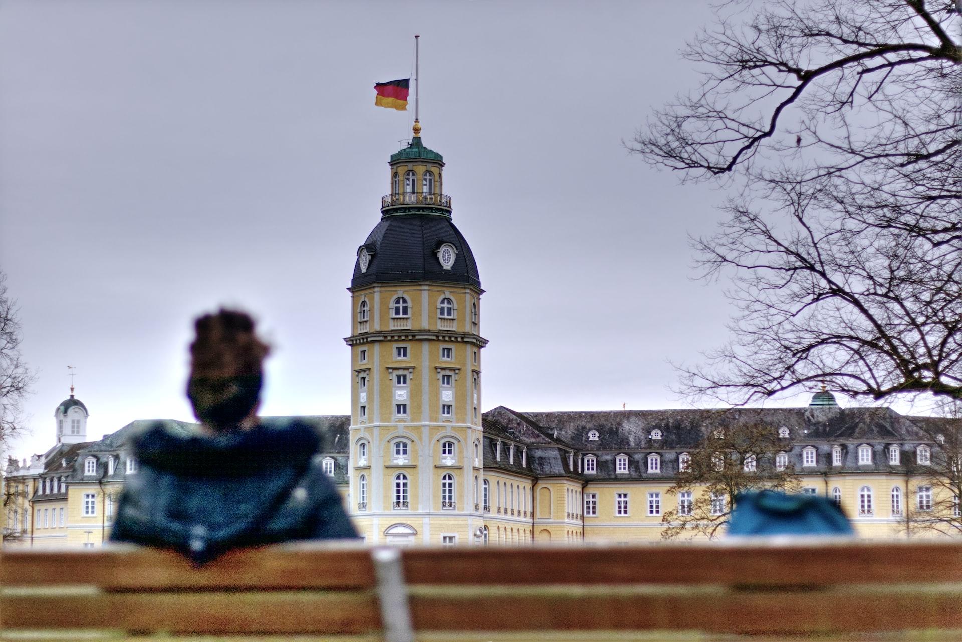 Eine Frau sitzt auf einer Bank vor dem Karlsruher Schloss.