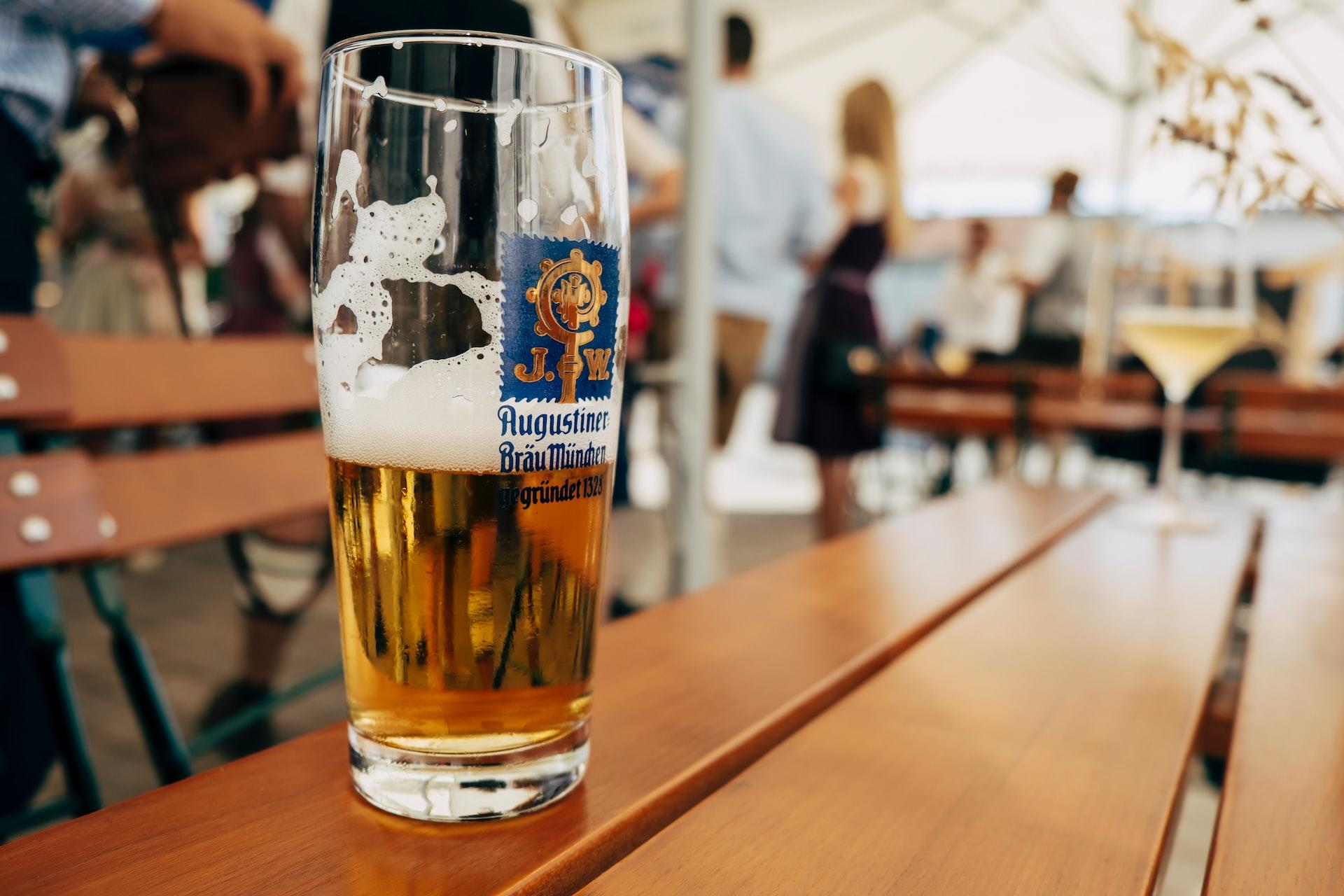 Auf einem Tisch in einem Biergarten steht ein halb ausgetrunkenes Bier.