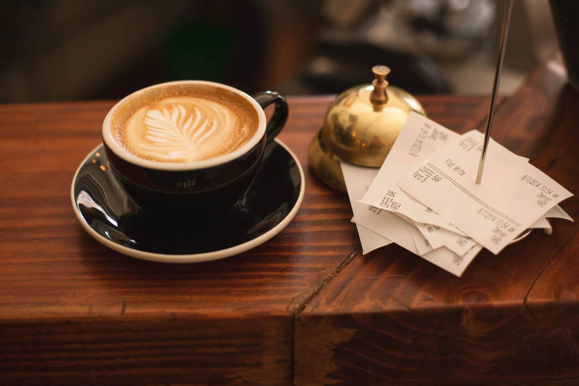 Auf einem Tresen steht eine Kaffee Tasse und mehrere Kassenbons.