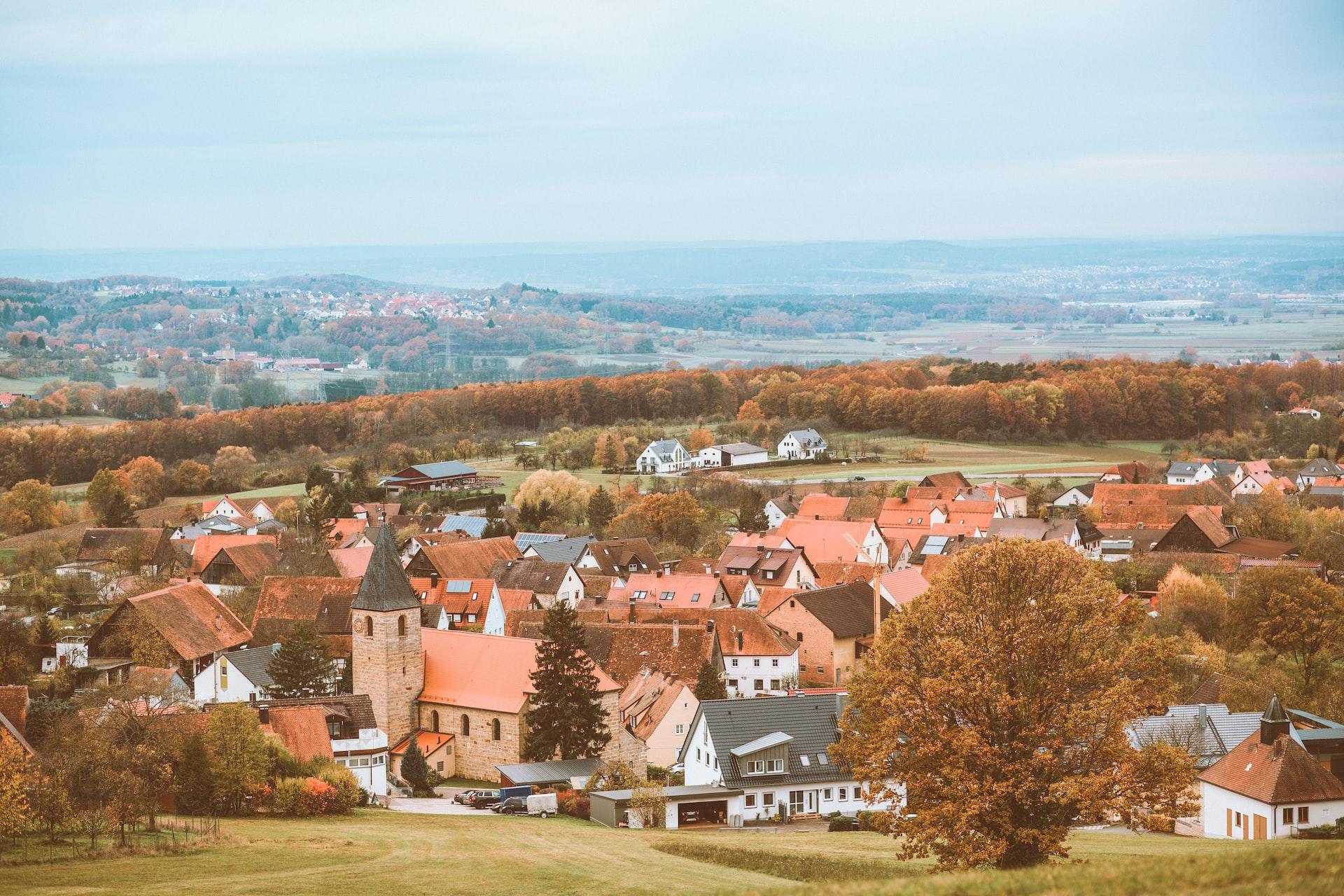 In einer ländlichen Region sind einige Häuser und eine Kirche zu sehen. 