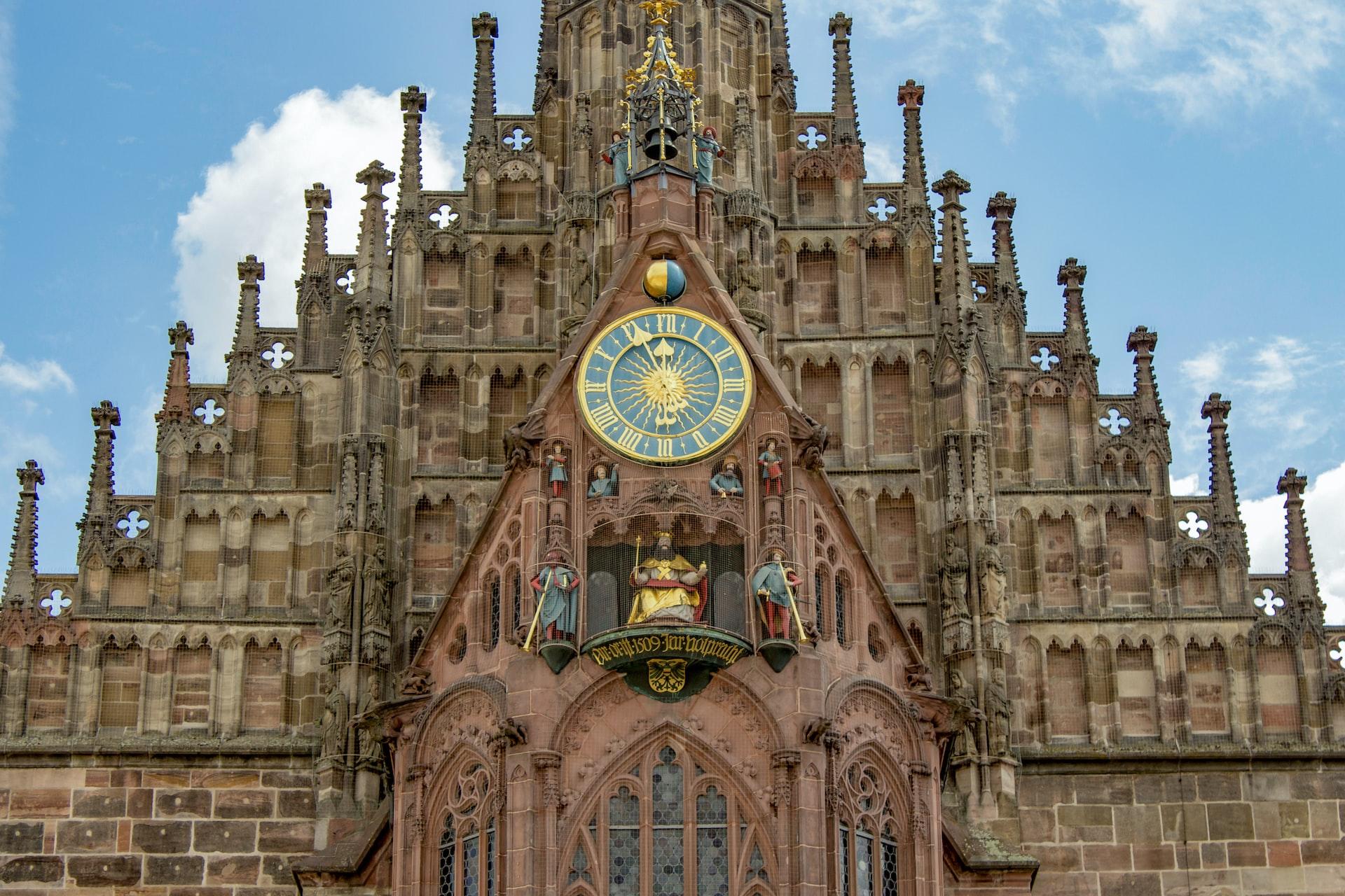 Eine alte Kirche mit Zifferblatt und im Hintergrund blauer Himmel.