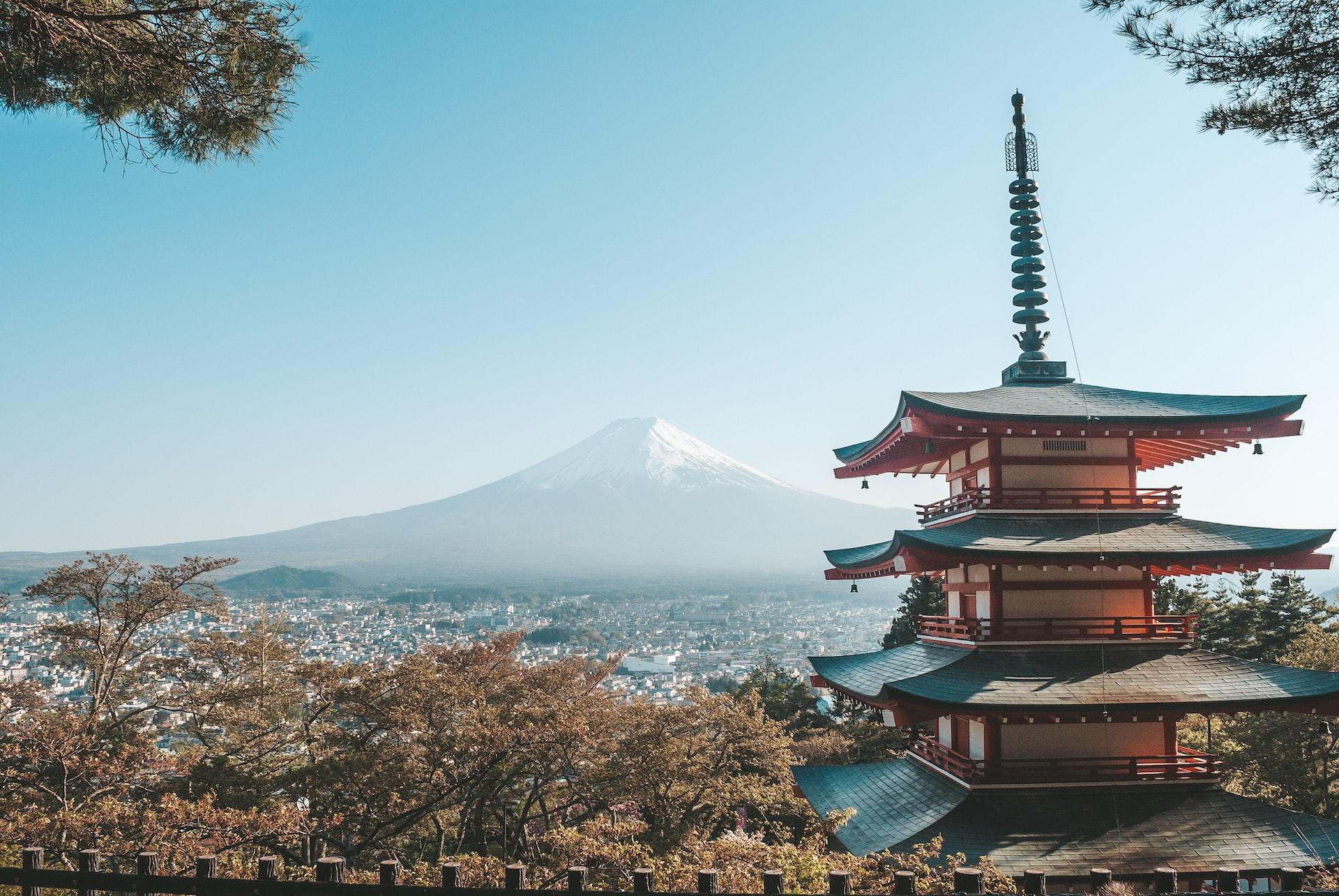 Hinter einem typisch japanischen Tempel ragt der Mount Fuji in den Himmel.