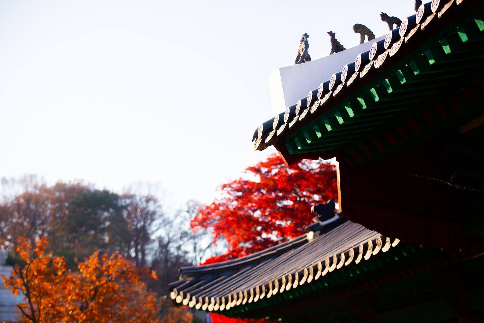 Auf dem Dach eines traditionellen koreanischen Gebäudes stehen kleine Figuren.