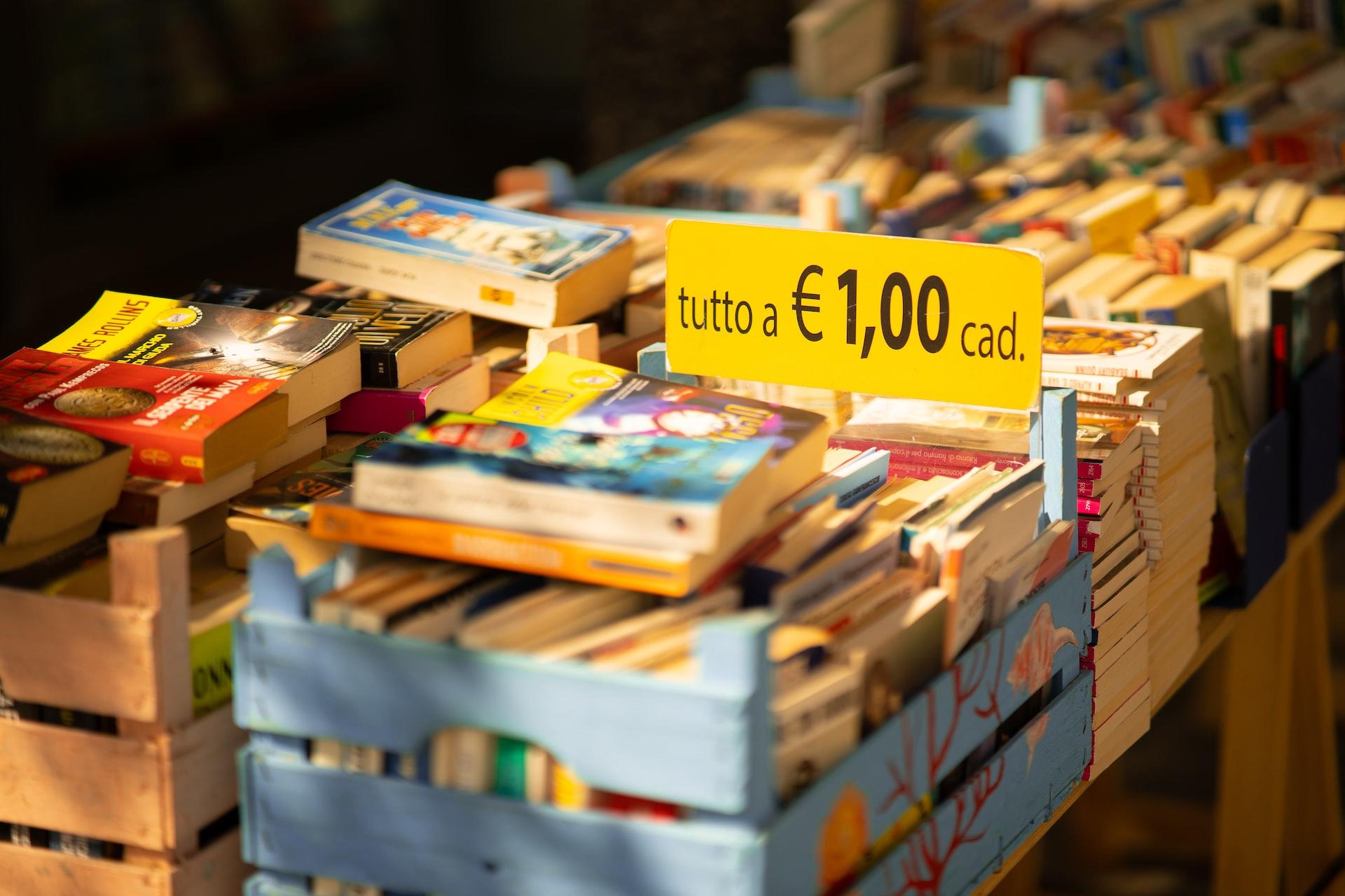 Auf einem Tisch steht eine Kiste mit Büchern, die für 1 Euro pro Stück verkauft werden.