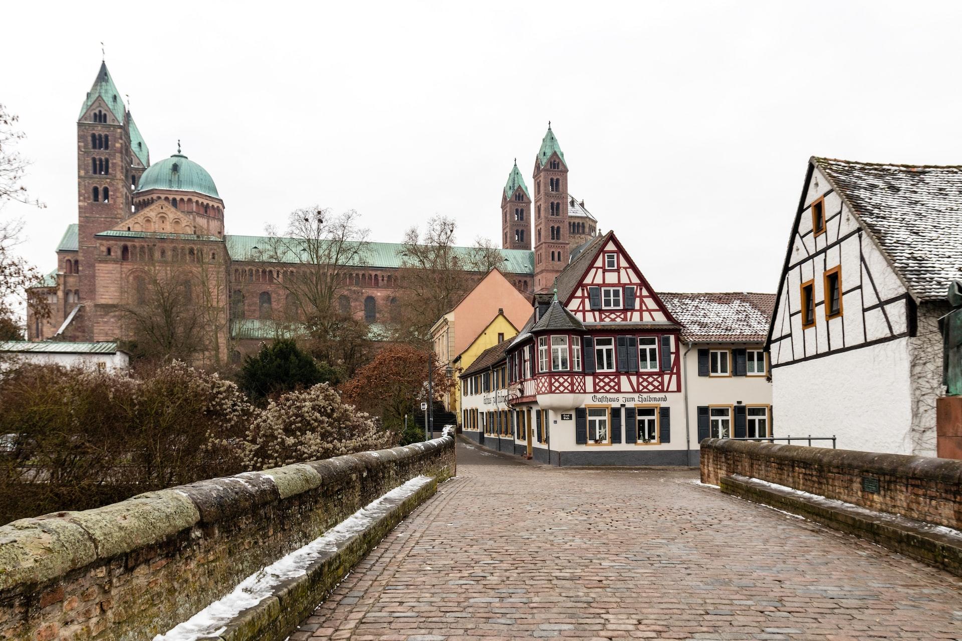 Blick auf den Dom von Speyer und rechts daneben einige alte Fachwerkhäuser.