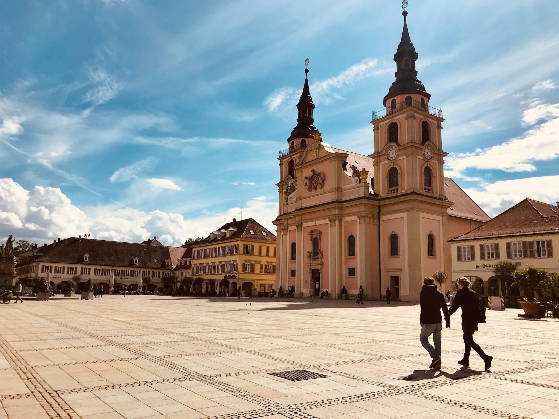 Zwei Menschen laufen über einen Platz vor einem Gebäude in Ludwigsburg. 