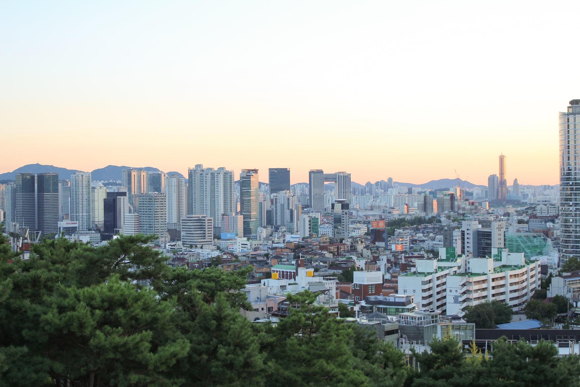 Zwischen Bäumen und Bergen ist der Blick auf die Skyline der Stadt Seoul frei.