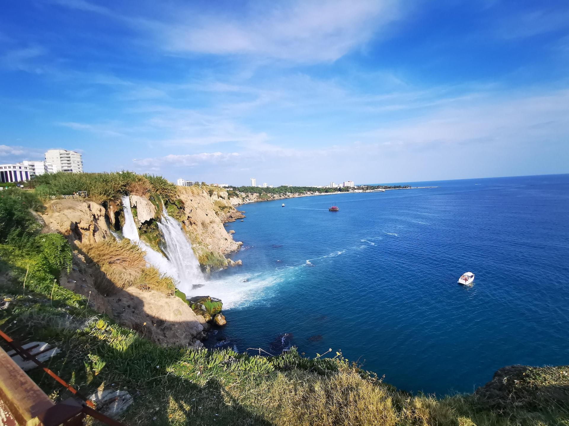 Über eine hohe Felsklippe hinab stürzt ein Wasserfall ins Meer hinein. 