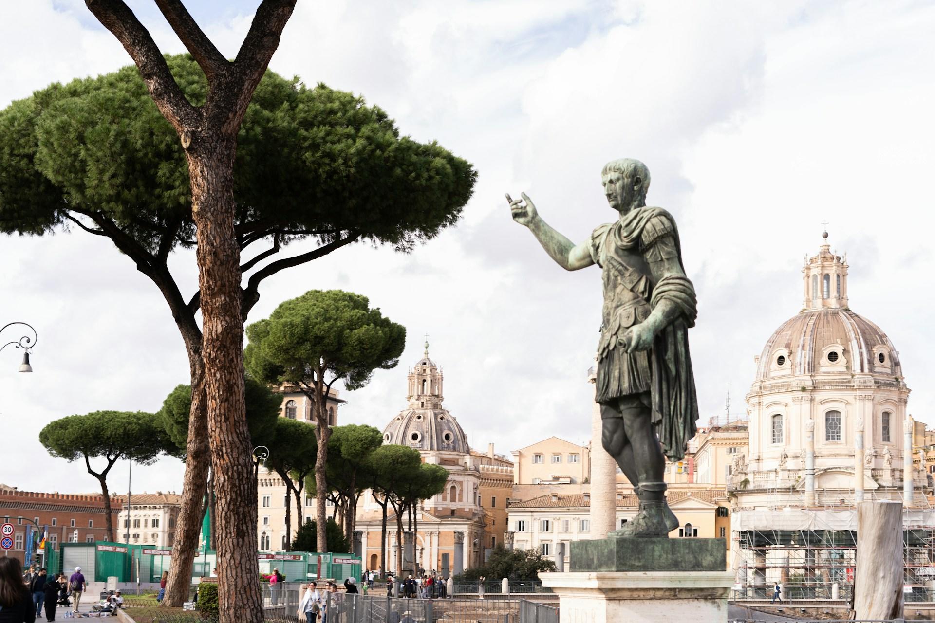 Statue vor Bäumen auf Sockel.