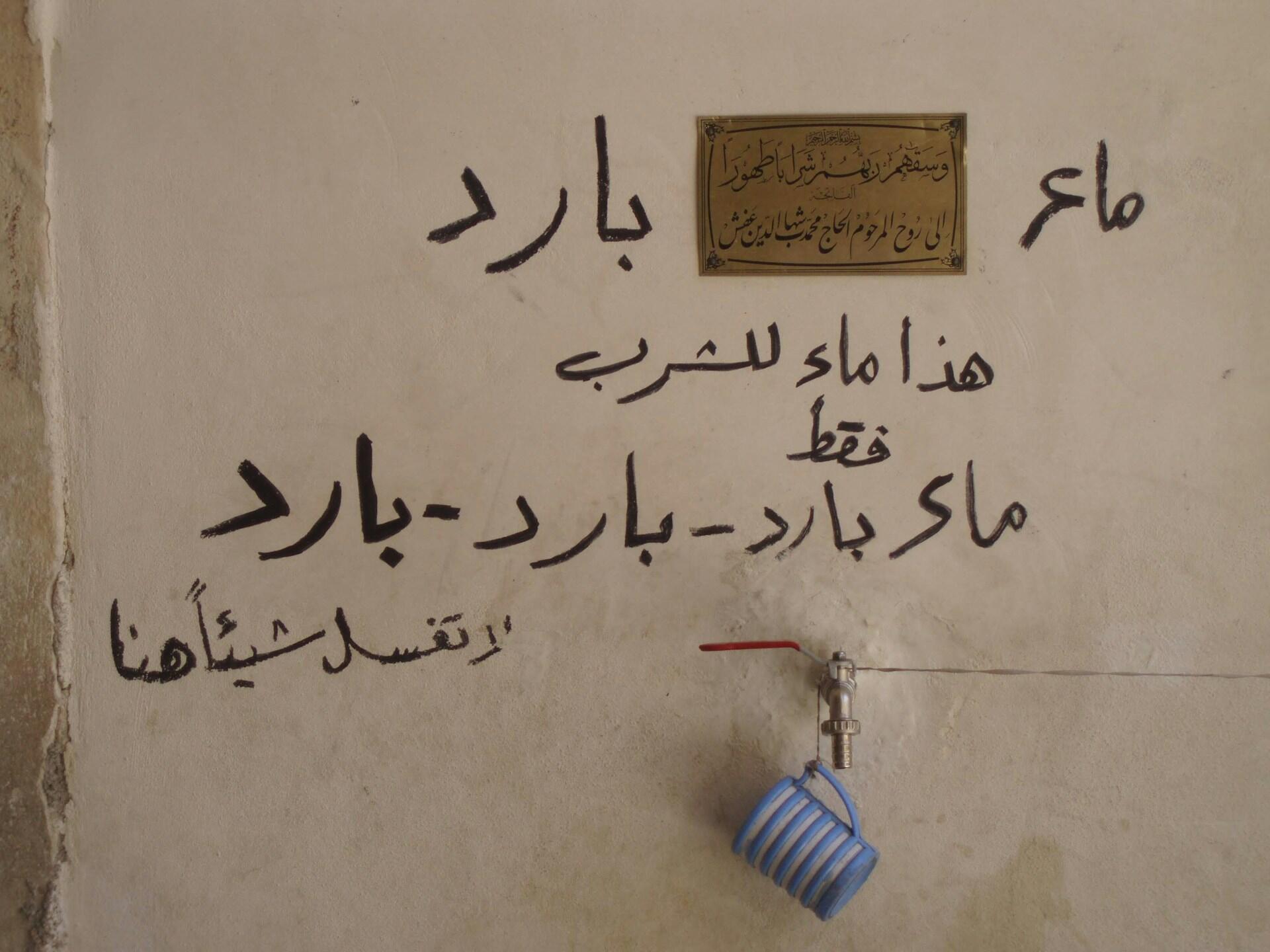 Arabischer Text an weißer Wand.