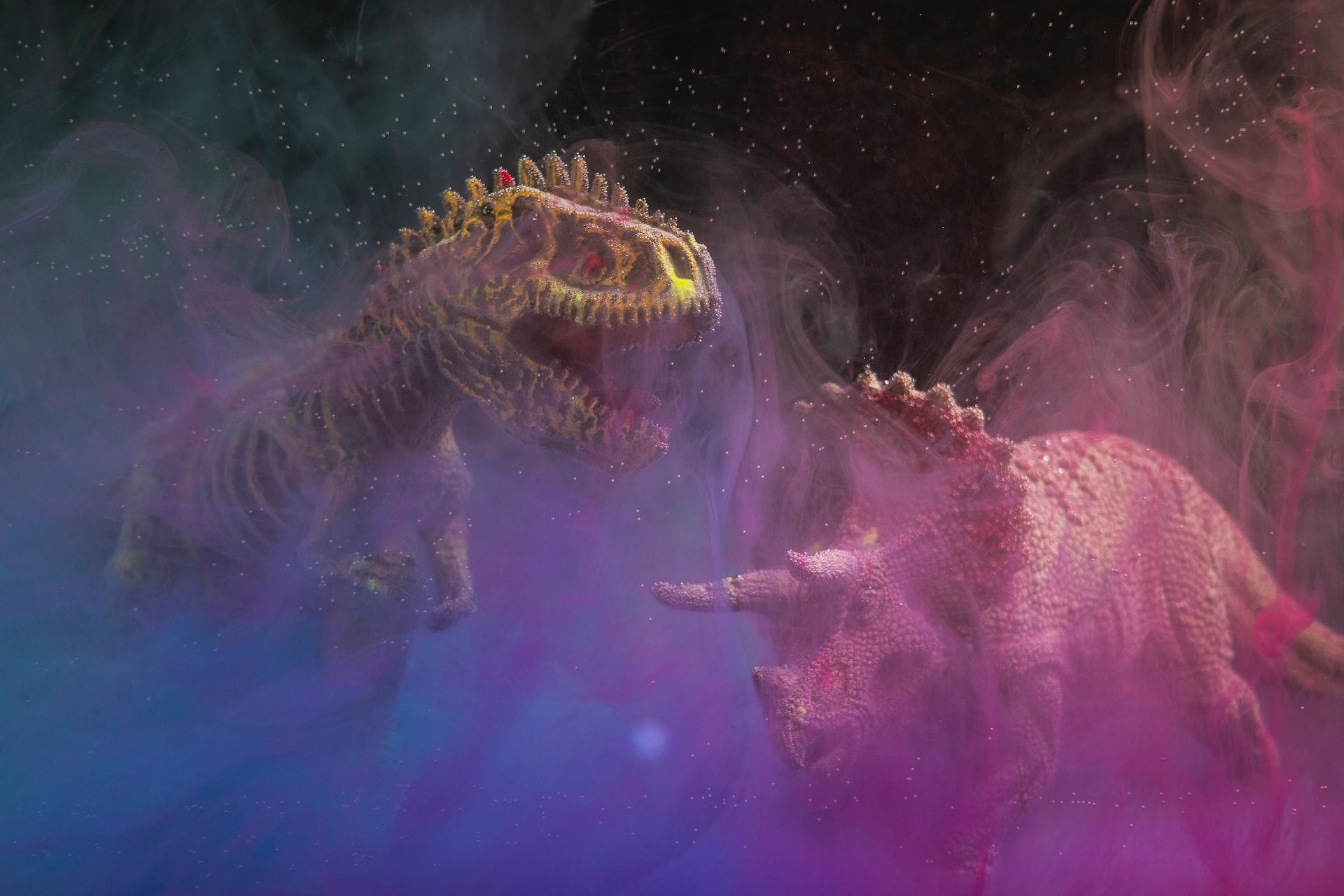 Die Modelle von zwei Dinosauriern sind umgeben von buntem Licht und Nebelschwaden. 
