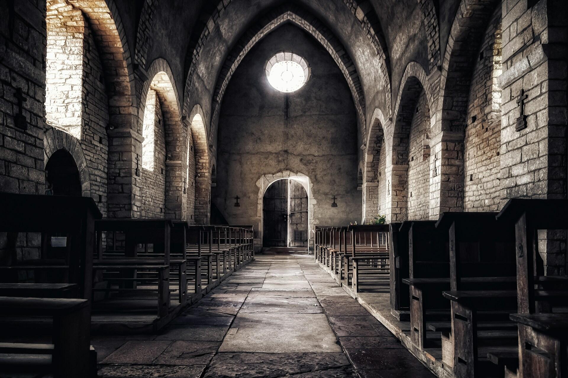 Kreuzgang einer Kirche aus Stein mit Bänken.