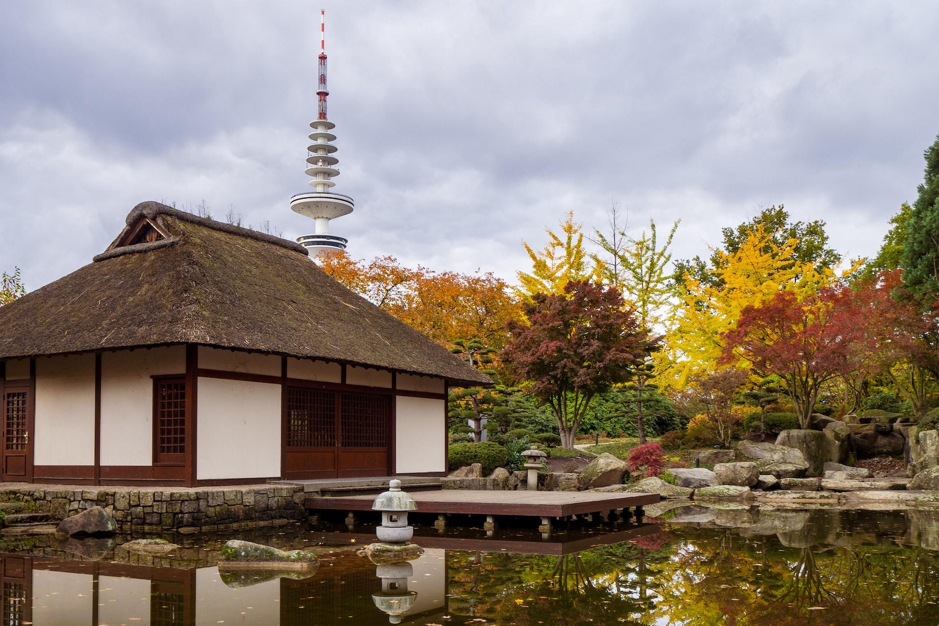 Ein traditionelles japanisches Gebäude steht in einer begrünten Umgebung vor einem Teich.