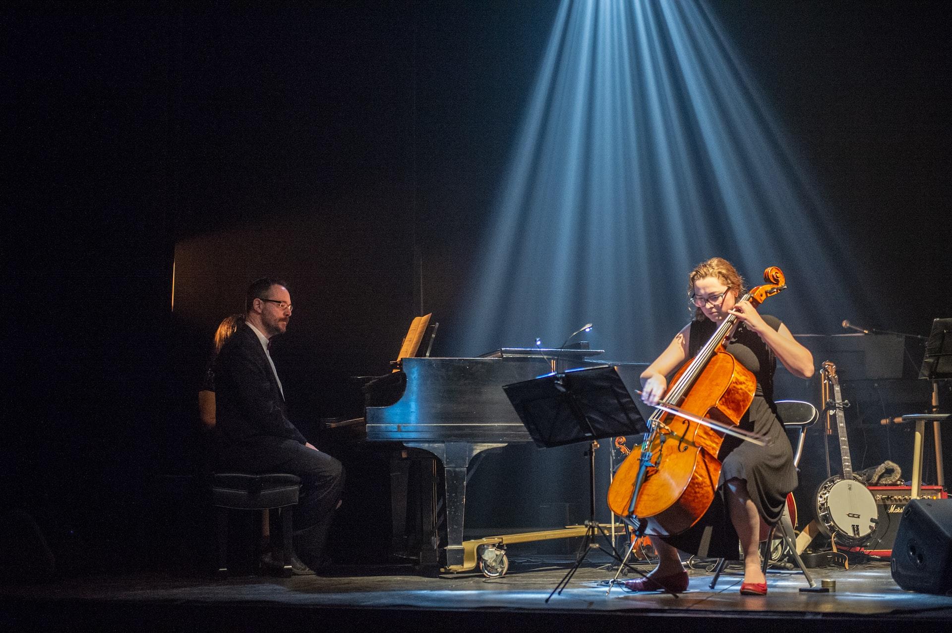 Auf einer Bühne sitzt eine Person an einem Flügel und eine andere an einem Cello.