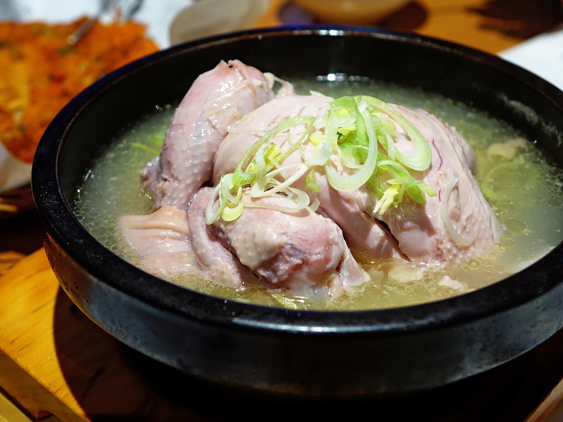 Huhn in Brühe in einem Topf mit Lauch. 