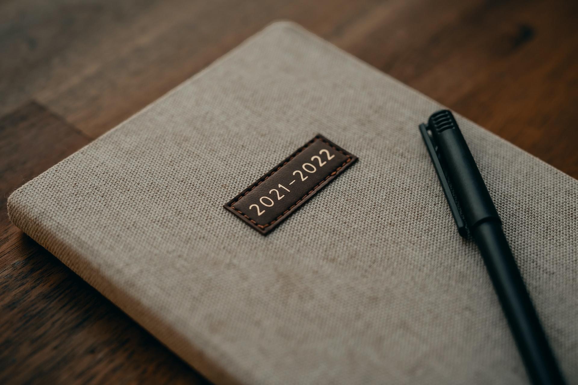 Auf einem Terminkalender der Jahre 2021 und 2022 liegt ein schwarzer Stift.