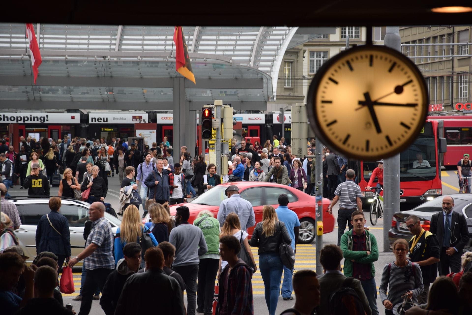 Berner Bahnhofsplatz zur Rush Hour mit sehr vielen Menschen und einer Uhr in der oberen rechten Ecke.