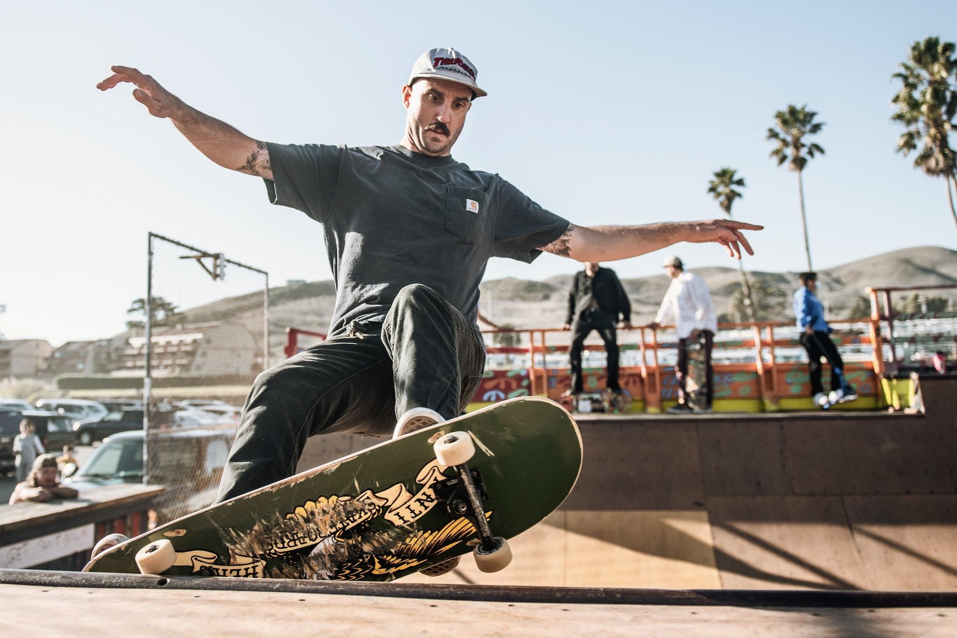 Eine Person mit einem Skateboard unter den Füßen ist am oberen Rand einer Halfpipe.