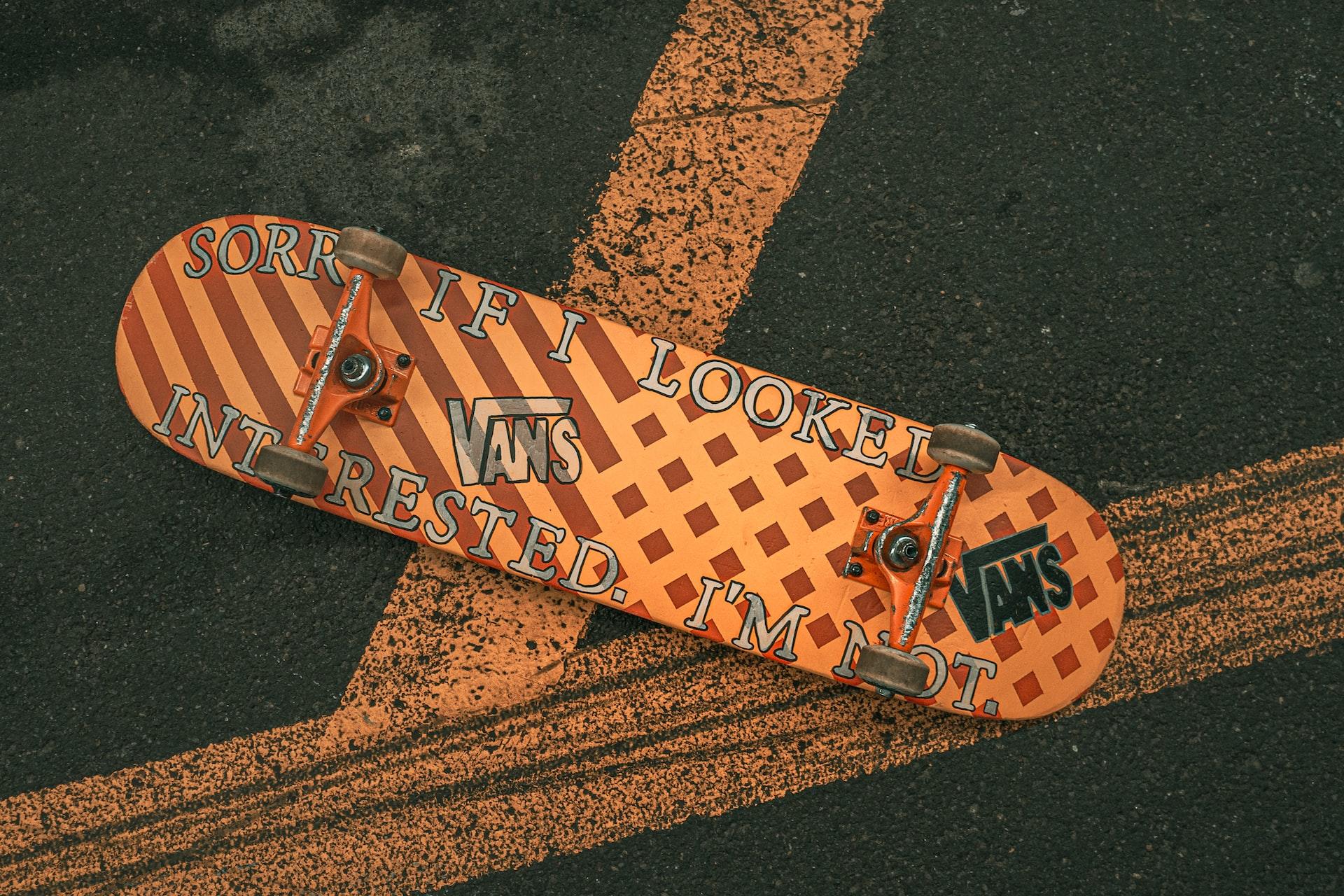 Ein auf der Unterseite beschriftetes Skateboard liegt mit den Rollen nach oben auf der Straße.