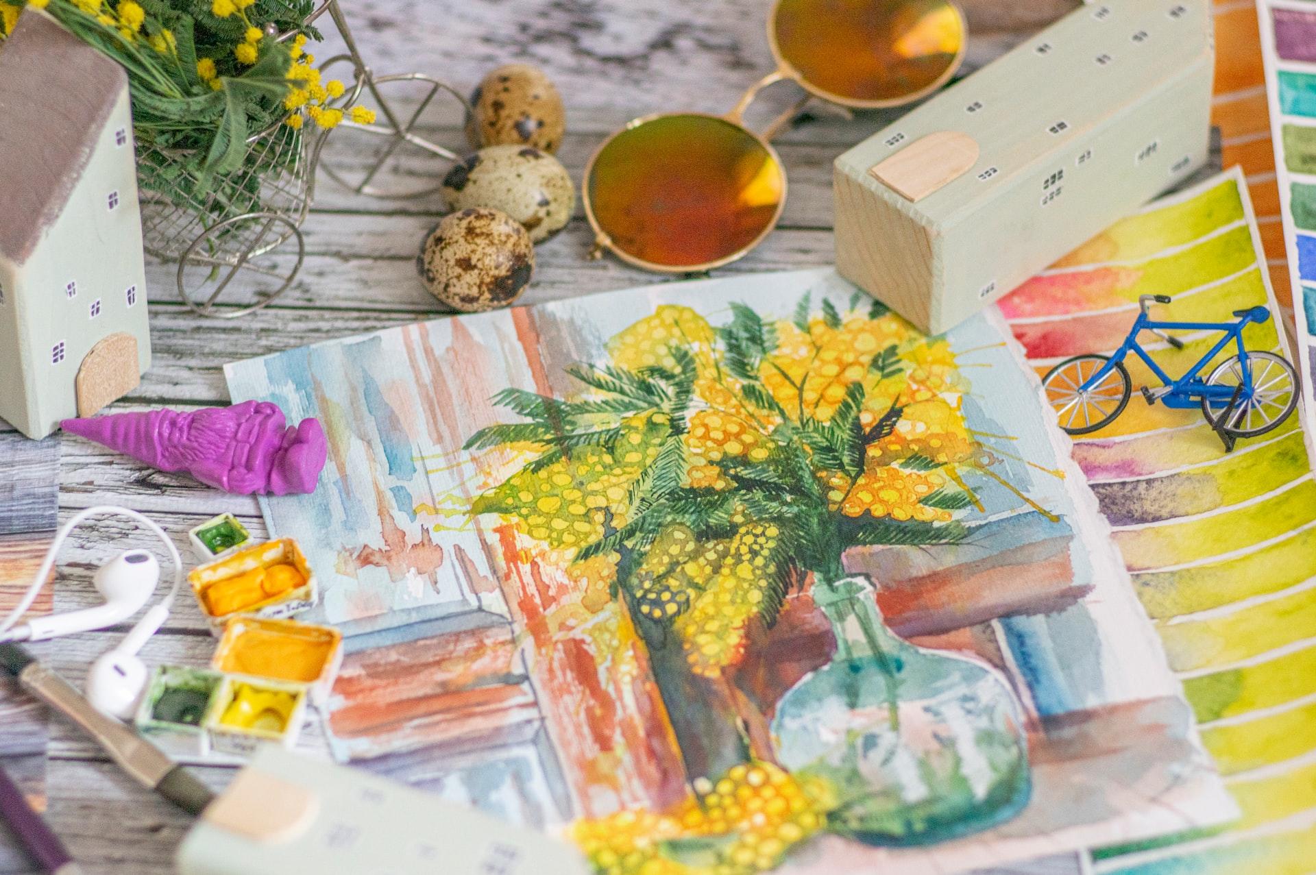 Auf einem Tisch liegt ein Bild von einer gelben Pflanze und daneben liegen weitere Gegenstände.