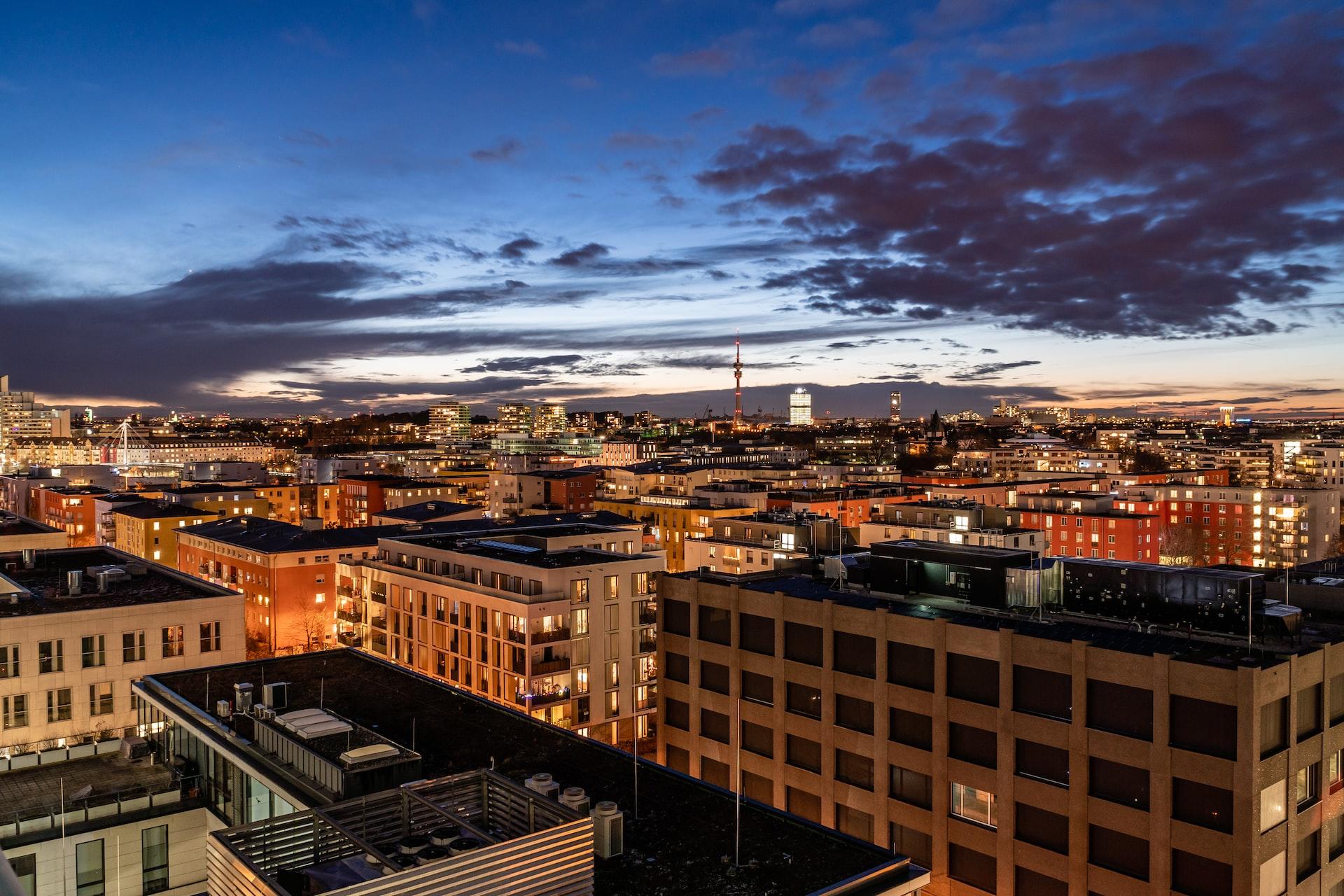 Im Abendlicht sind Gebäude hell erleuchtet und der Blick führt über die Dächer zum Horizont.