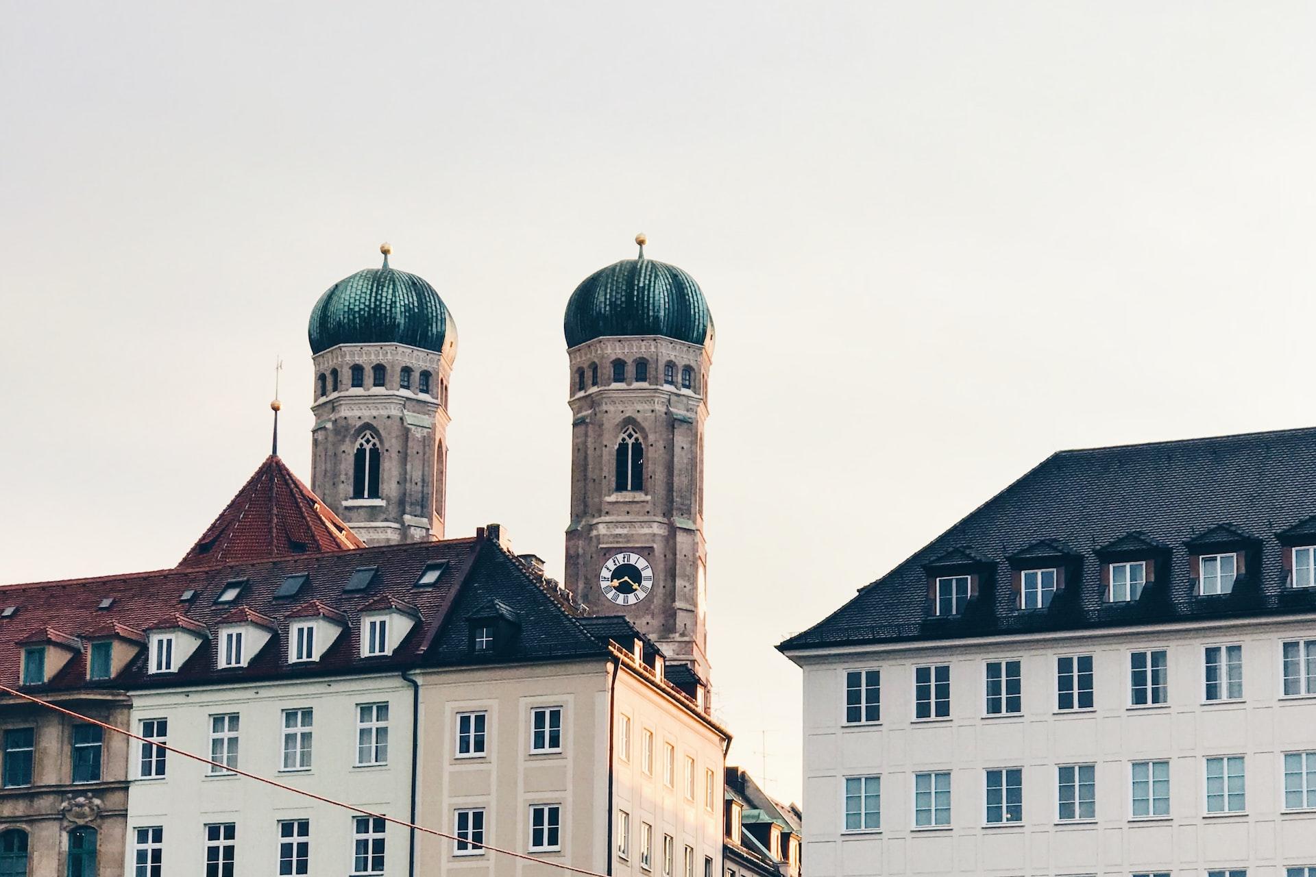 Über zwei Häusern sind zwei Türme mit grüner Spitze zu sehen.