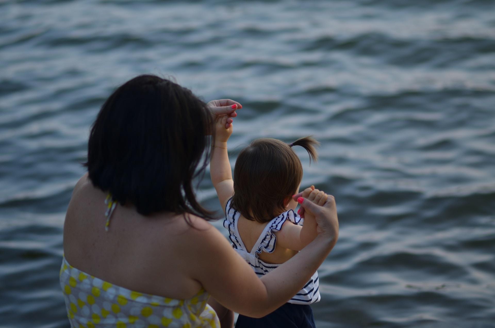 Frau mit Kind an der Hand im Wasser.