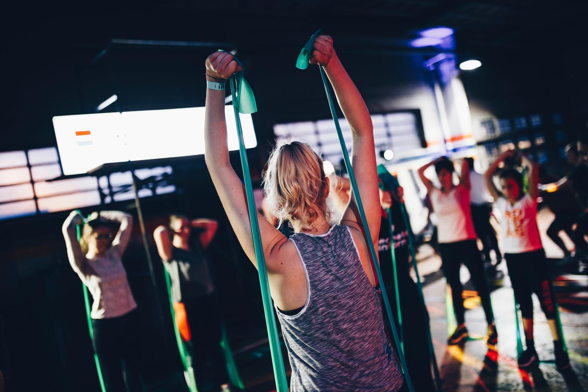 Mehrere Menschen in Sportklamotten mit elastischen Bändern in den Händen.